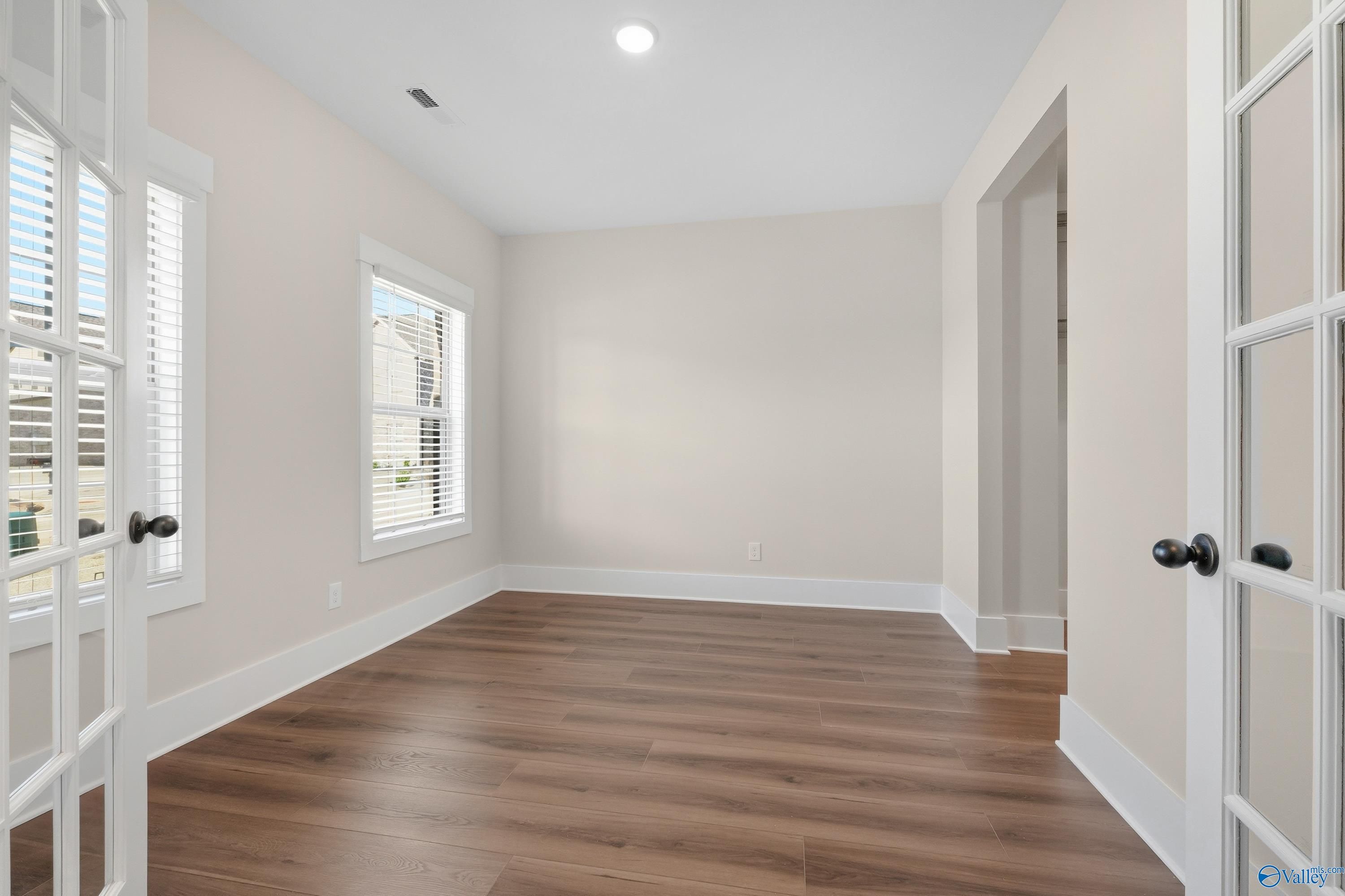 Bright secondary bedroom with hardwood floors, French doors, and arched entry in Davidson Homes The Shelby A, Athens AL