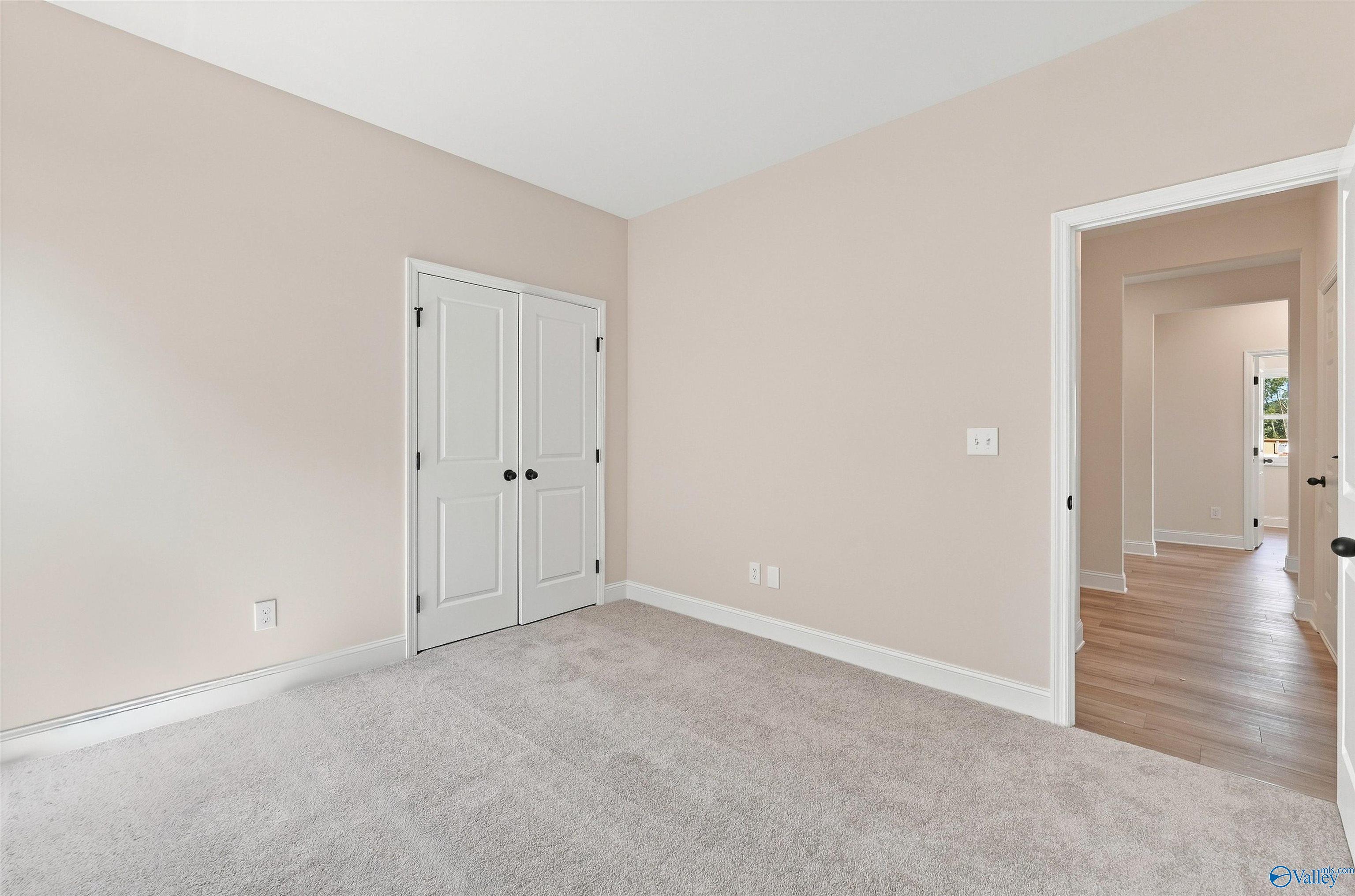 Bright bedroom with plush carpet and white double-door closet in Davidson Homes The Everett B, Ivy Hills, Toney, Alabama