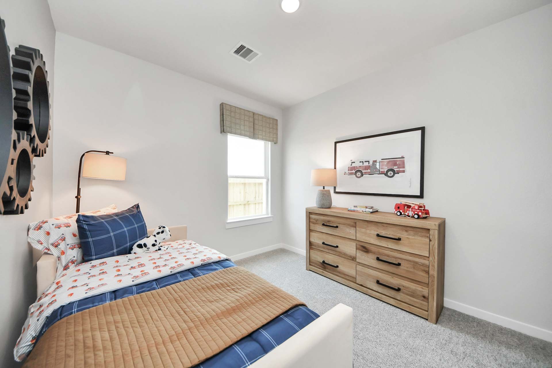 Kids' bedroom with fire truck decor and wooden dresser at Enclave at Newport in Crosby, TX by Davidson Homes.