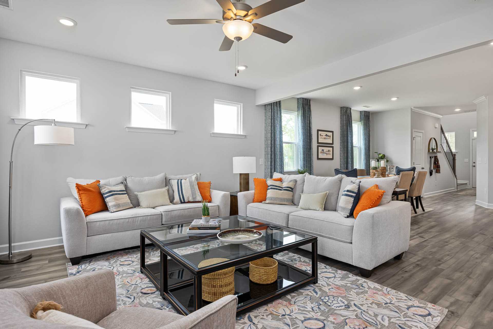 Spacious open-concept living room at Beverly Place in Four Oaks NC by Davidson Homes with neutral sofas, glass coffee table, and hardwood floors