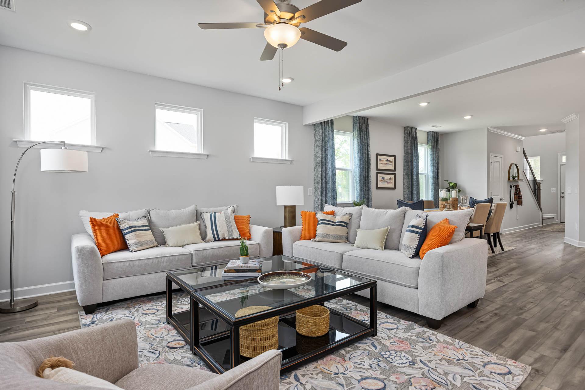 Spacious open-concept living room at Beverly Place in Four Oaks NC by Davidson Homes with neutral sofas, glass coffee table, and hardwood floors