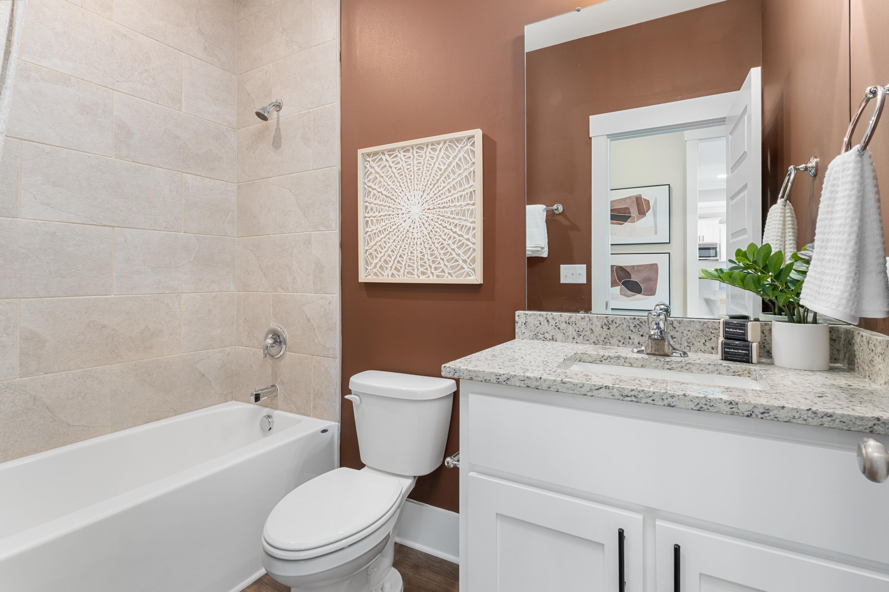 Luxurious master bathroom in The Shelby A by Davidson Homes featuring soaking tub, walk-in shower, granite vanity, and beige tile accents