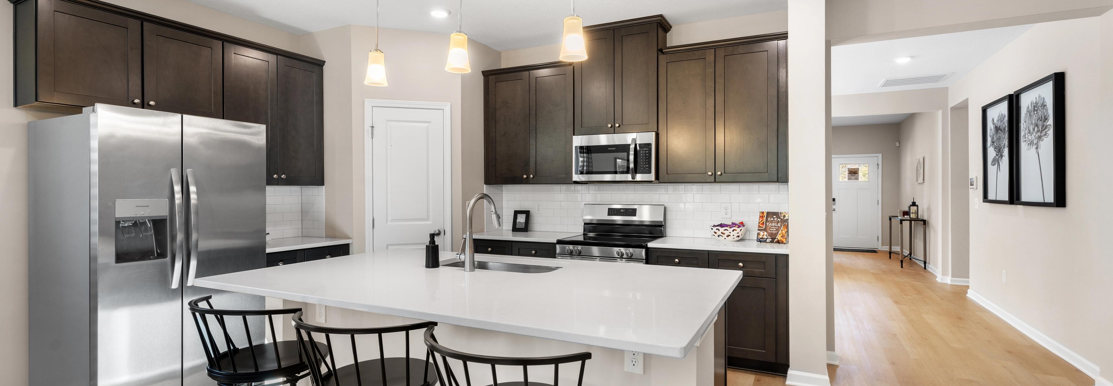 Spacious open-concept kitchen at Silver Oak in Cusseta Alabama with dark cabinets white island farmhouse table and hardwood floors