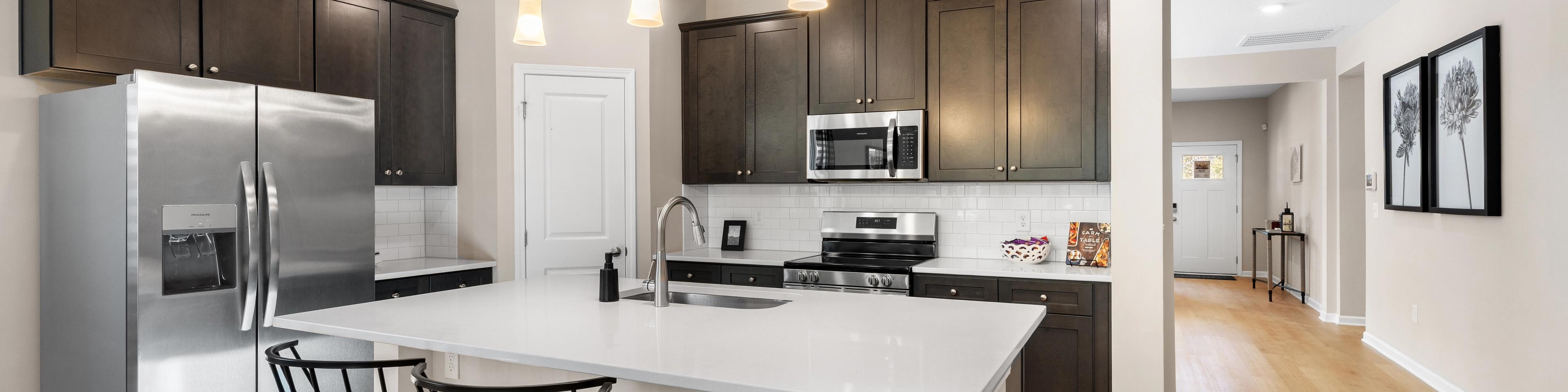 Spacious open-concept kitchen at Silver Oak in Cusseta Alabama with dark cabinets white island farmhouse table and hardwood floors