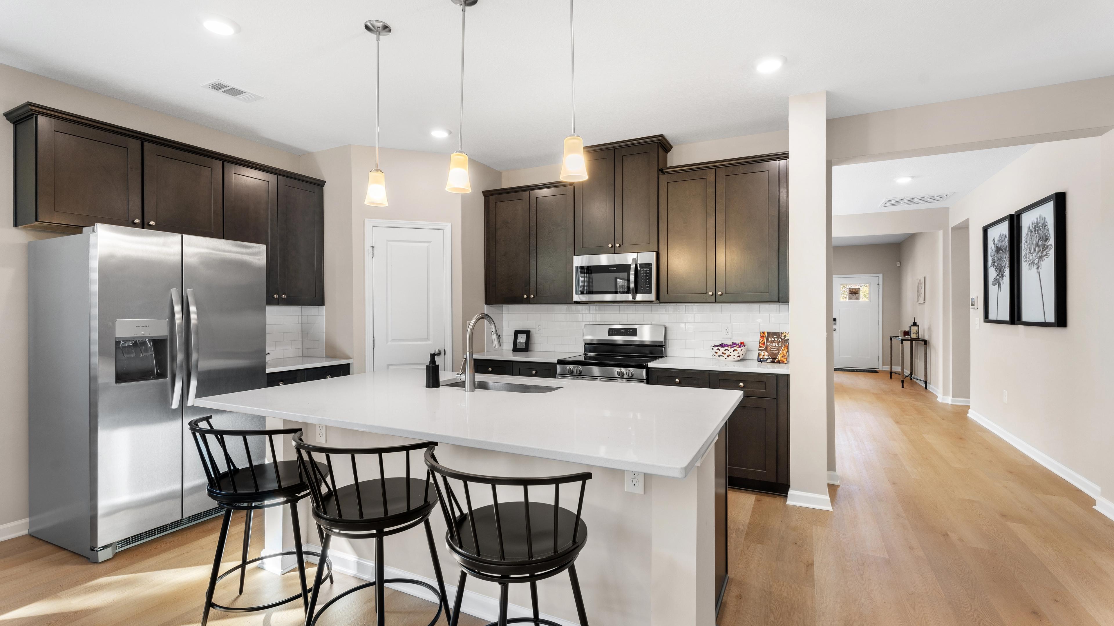 Spacious open-concept kitchen at Silver Oak in Cusseta Alabama with dark cabinets white island farmhouse table and hardwood floors
