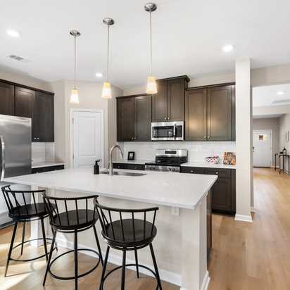 Spacious open-concept kitchen at Silver Oak in Cusseta Alabama with dark cabinets white island farmhouse table and hardwood floors