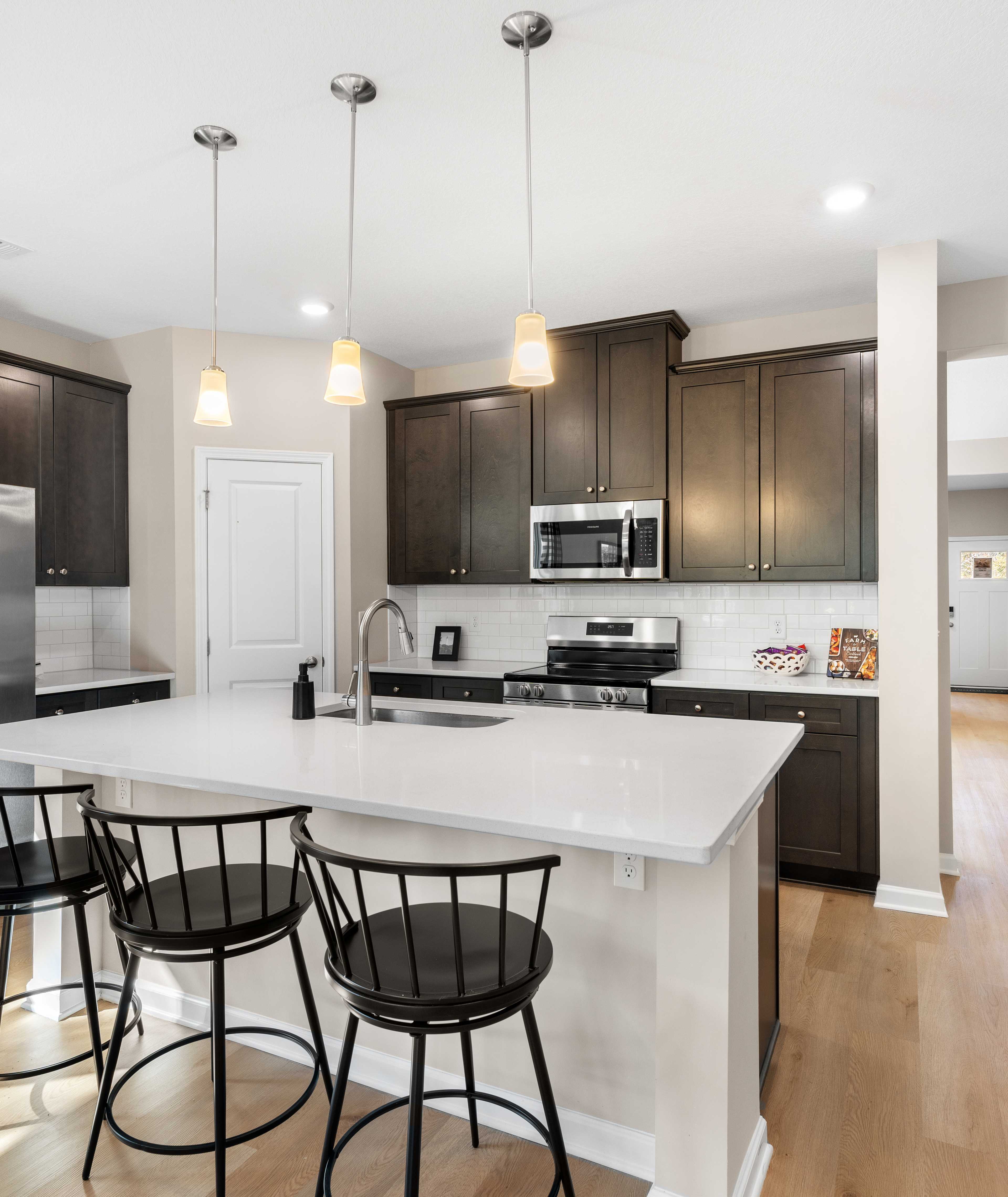 Spacious open-concept kitchen at Silver Oak in Cusseta Alabama with dark cabinets white island farmhouse table and hardwood floors