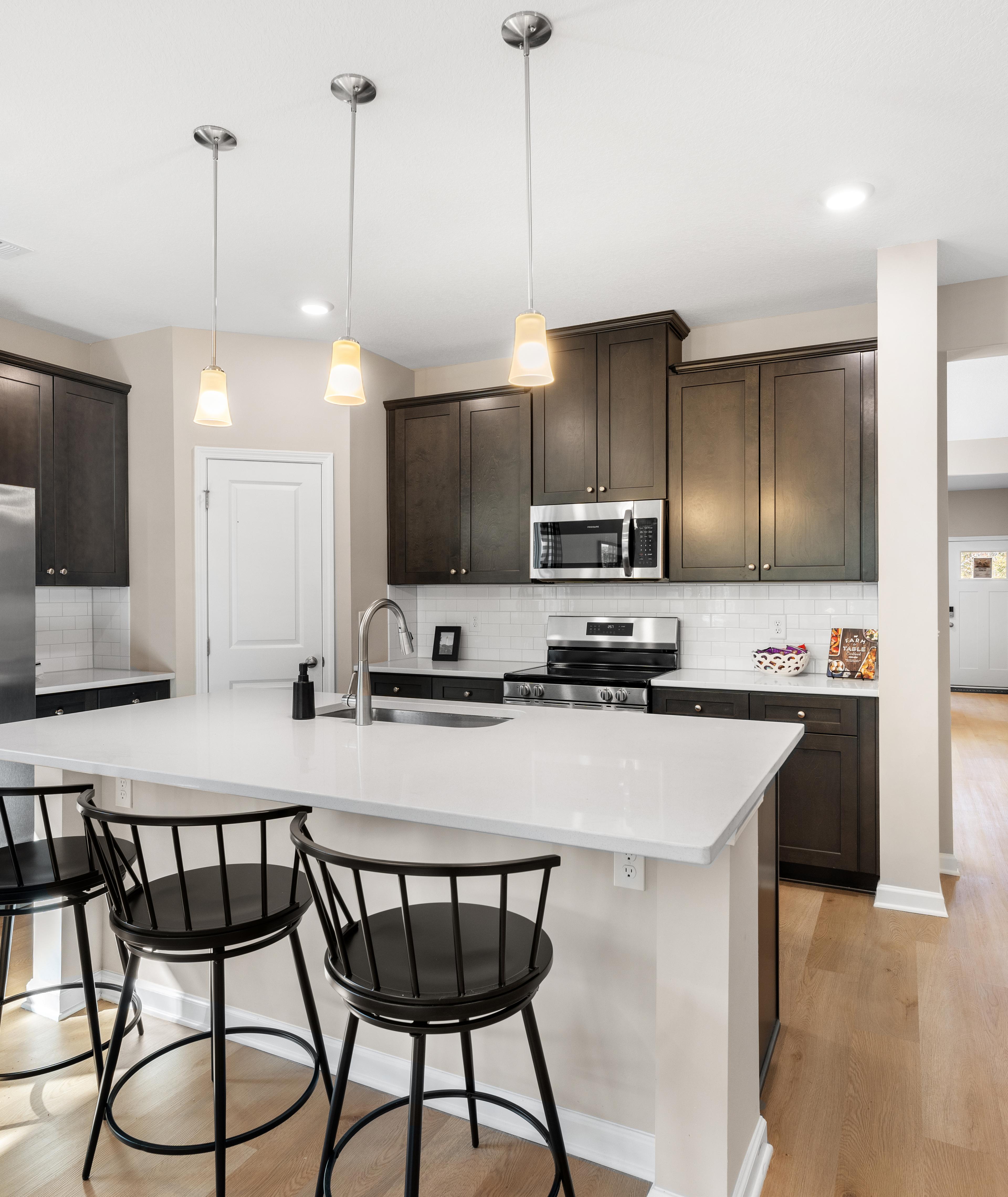 Spacious open-concept kitchen at Silver Oak in Cusseta Alabama with dark cabinets white island farmhouse table and hardwood floors