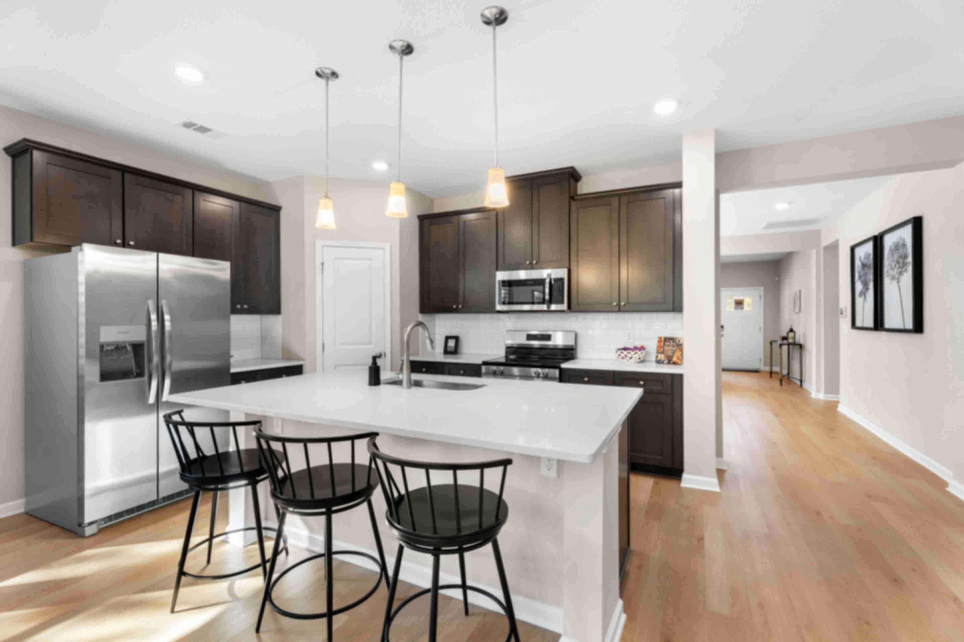 Spacious open-concept kitchen at Silver Oak in Cusseta Alabama with dark cabinets white island farmhouse table and hardwood floors
