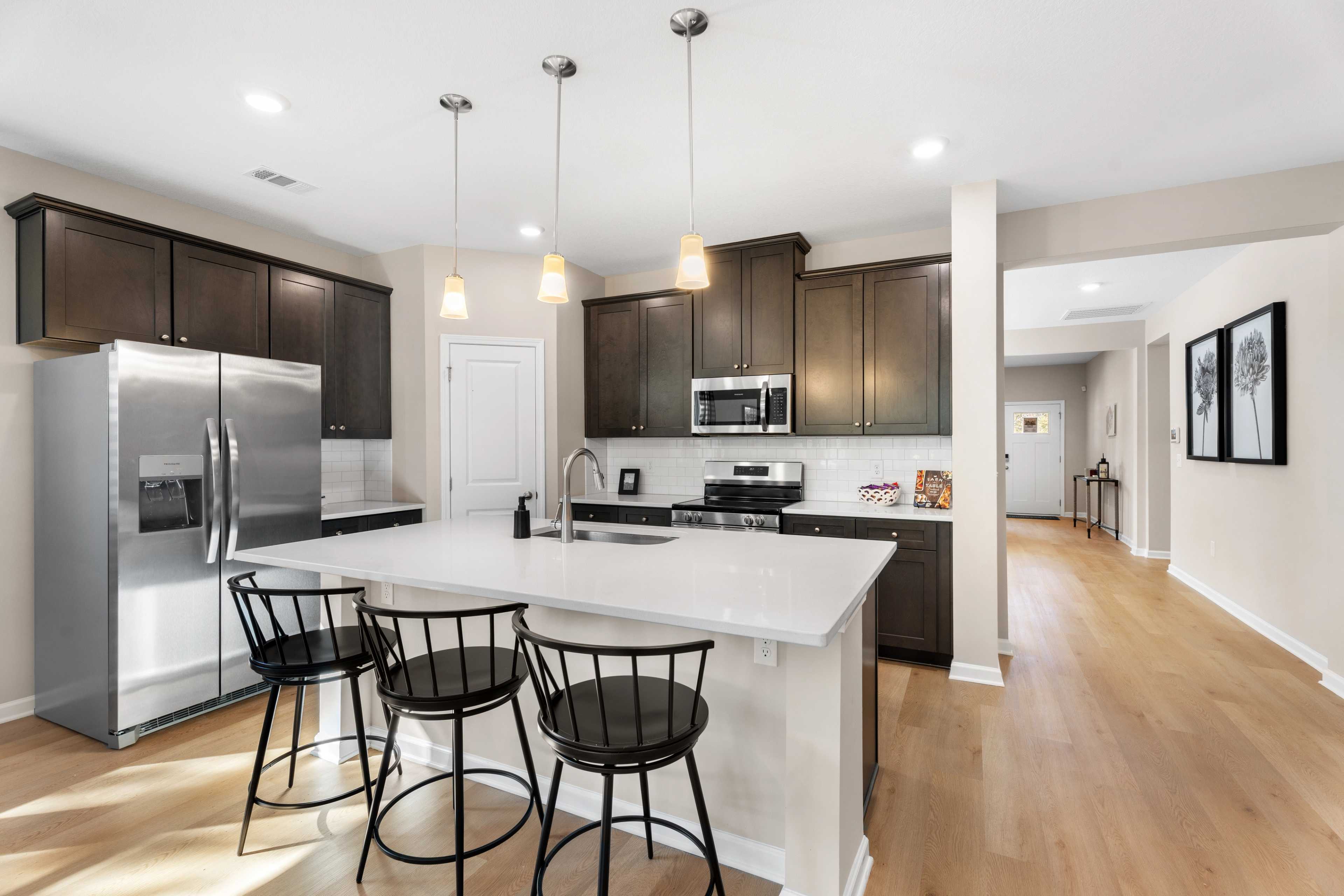 Spacious open-concept kitchen at Silver Oak in Cusseta Alabama with dark cabinets white island farmhouse table and hardwood floors