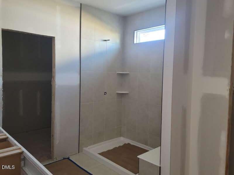 Spacious walk-in shower with subway tile walls, built-in bench, and glass enclosure in master bath of Davidson Homes The Magnolia B, Angier, NC