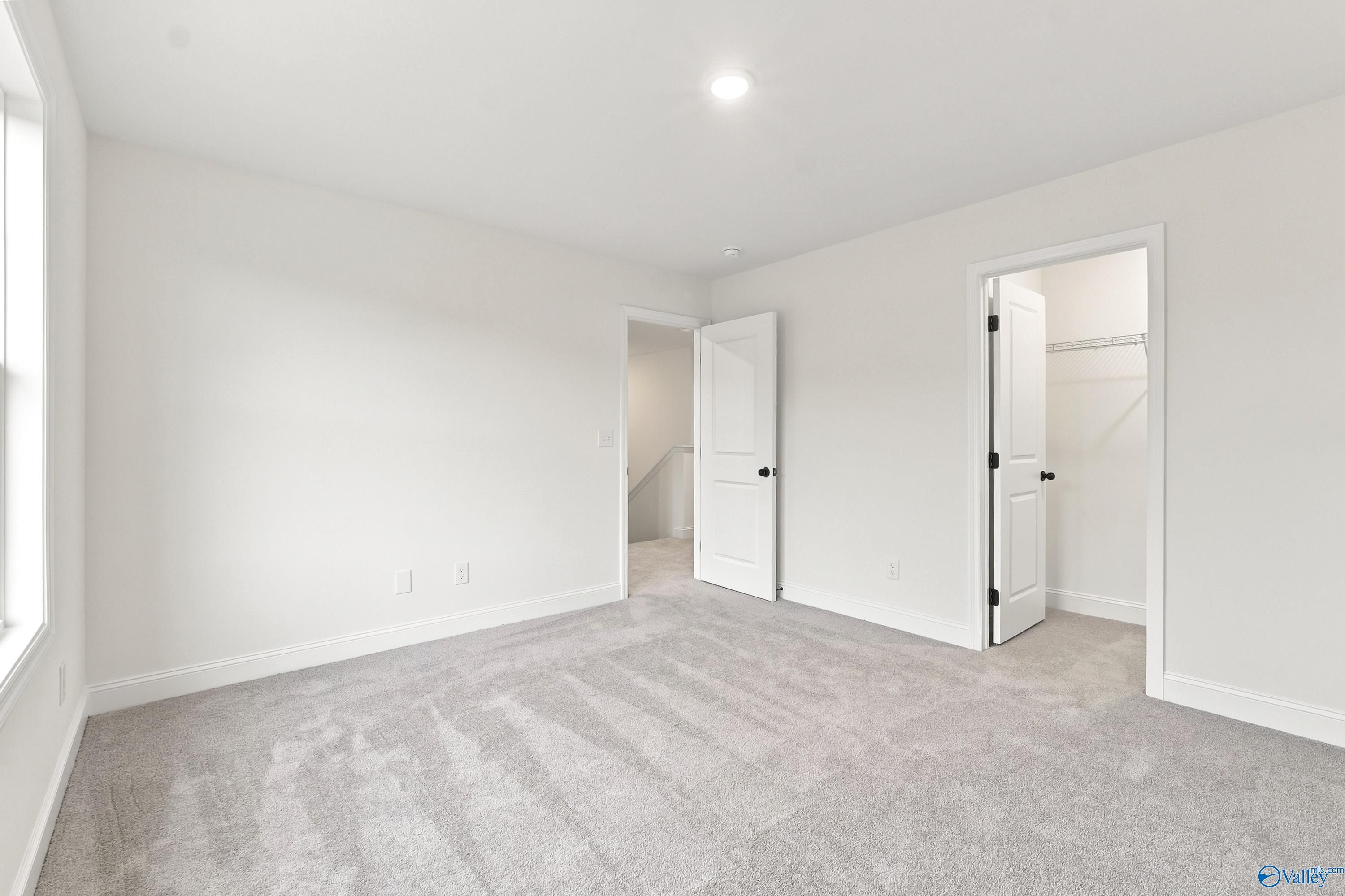 Bright, spacious secondary bedroom with plush carpeting and walk-in closet in The Shelby D floor plan, Noble Ridge, Cullman.