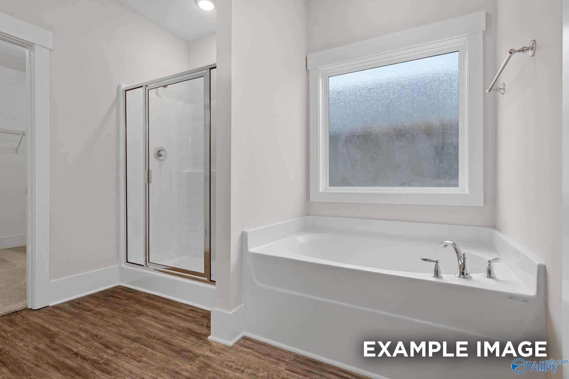 Elegant master bathroom with glass shower and corner soaking tub in The Everett B by Davidson Homes, Athens AL