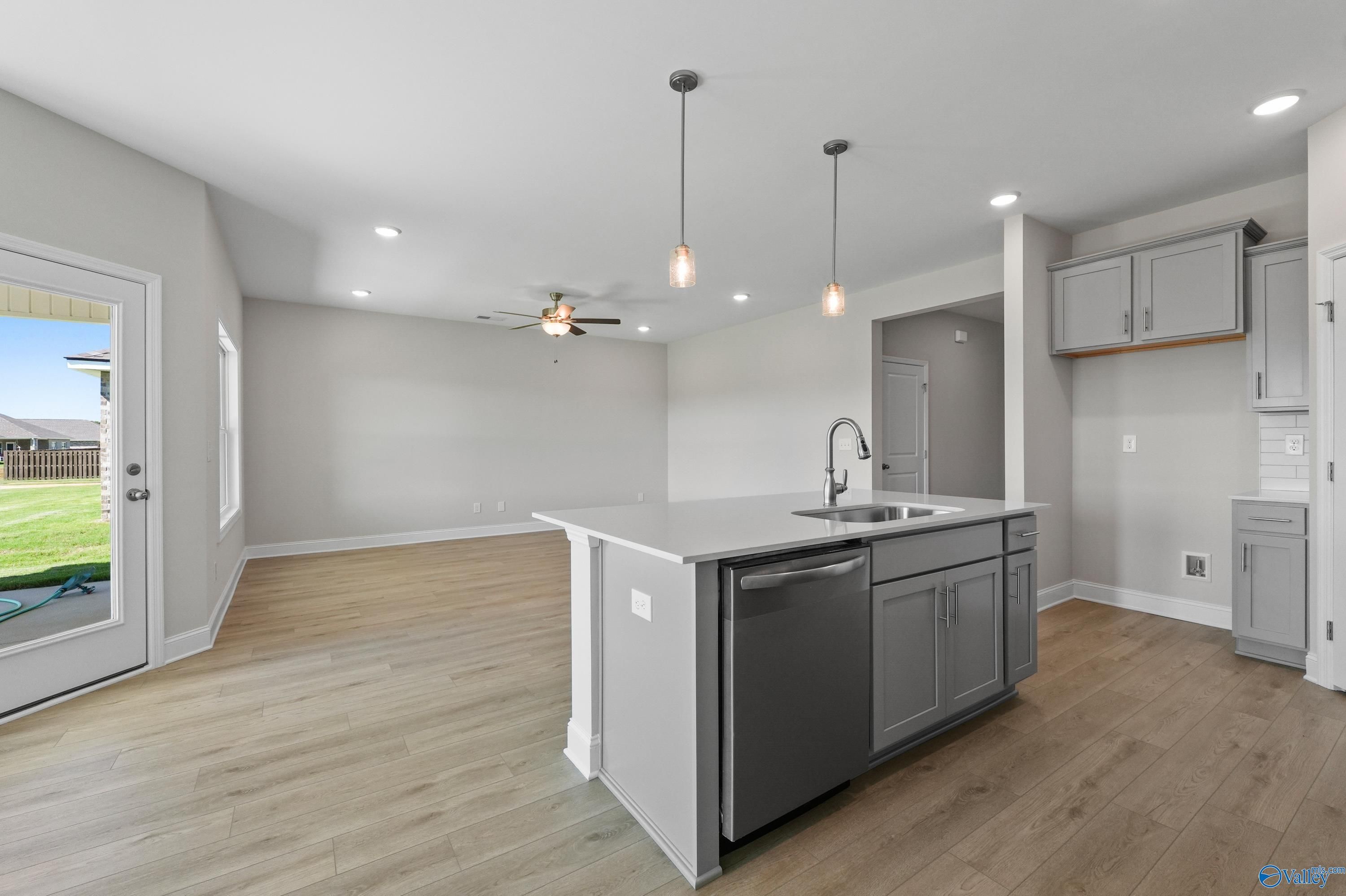 Modern open-concept kitchen with gray island sink, dishwasher, and sliding doors to backyard in Davidson Homes The Everett, Hazel Green, AL