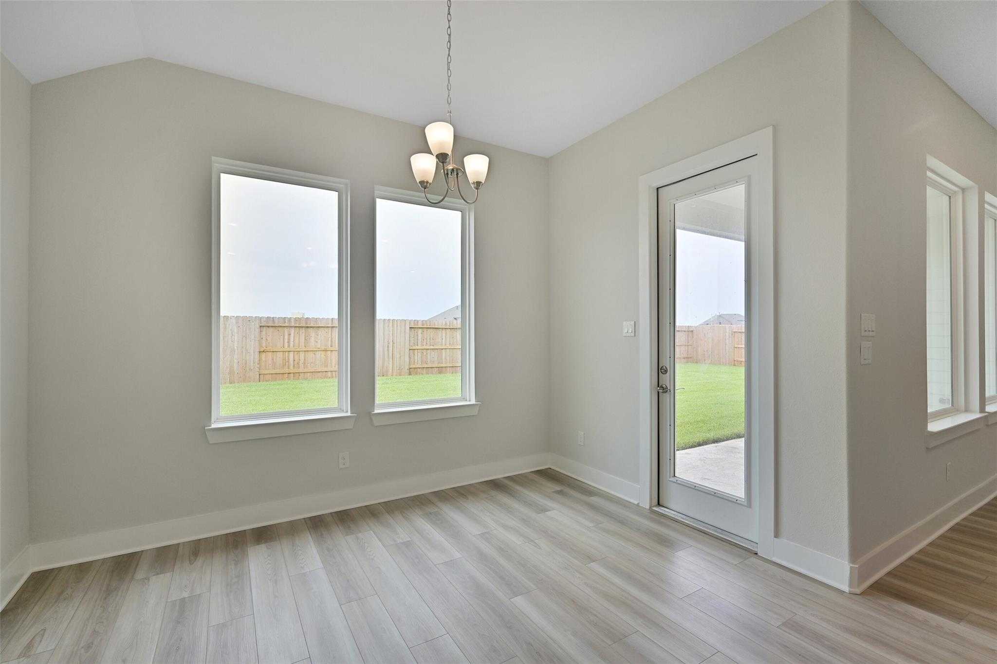 Bright dining room with chandelier, large windows, and backyard view in Davidson Homes The Edward A, Lago Mar, Texas City
