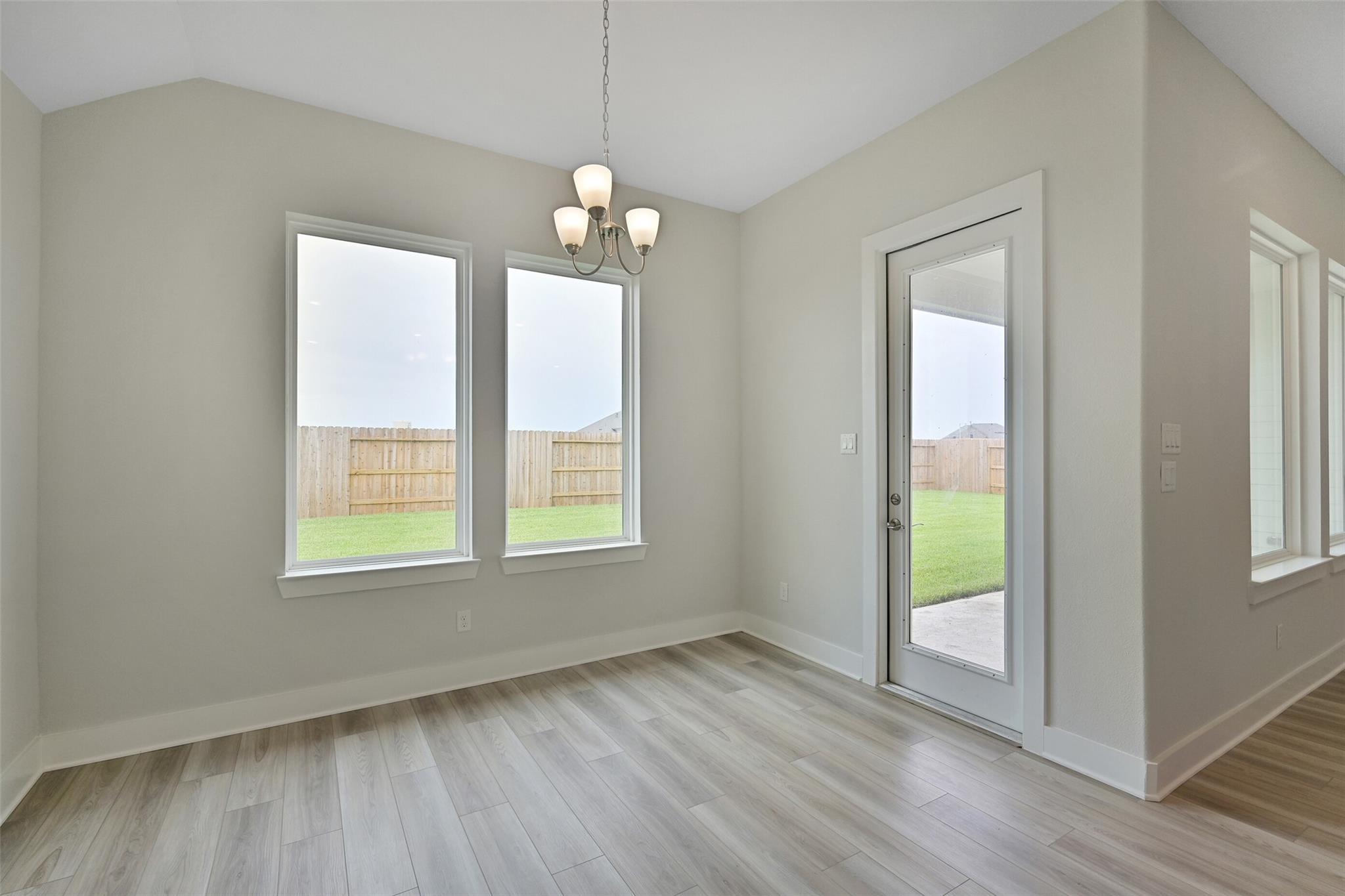 Bright dining room with chandelier, large windows overlooking lush backyard, glass door in Davidson Homes The Edward A, Lago Mar, Texas City