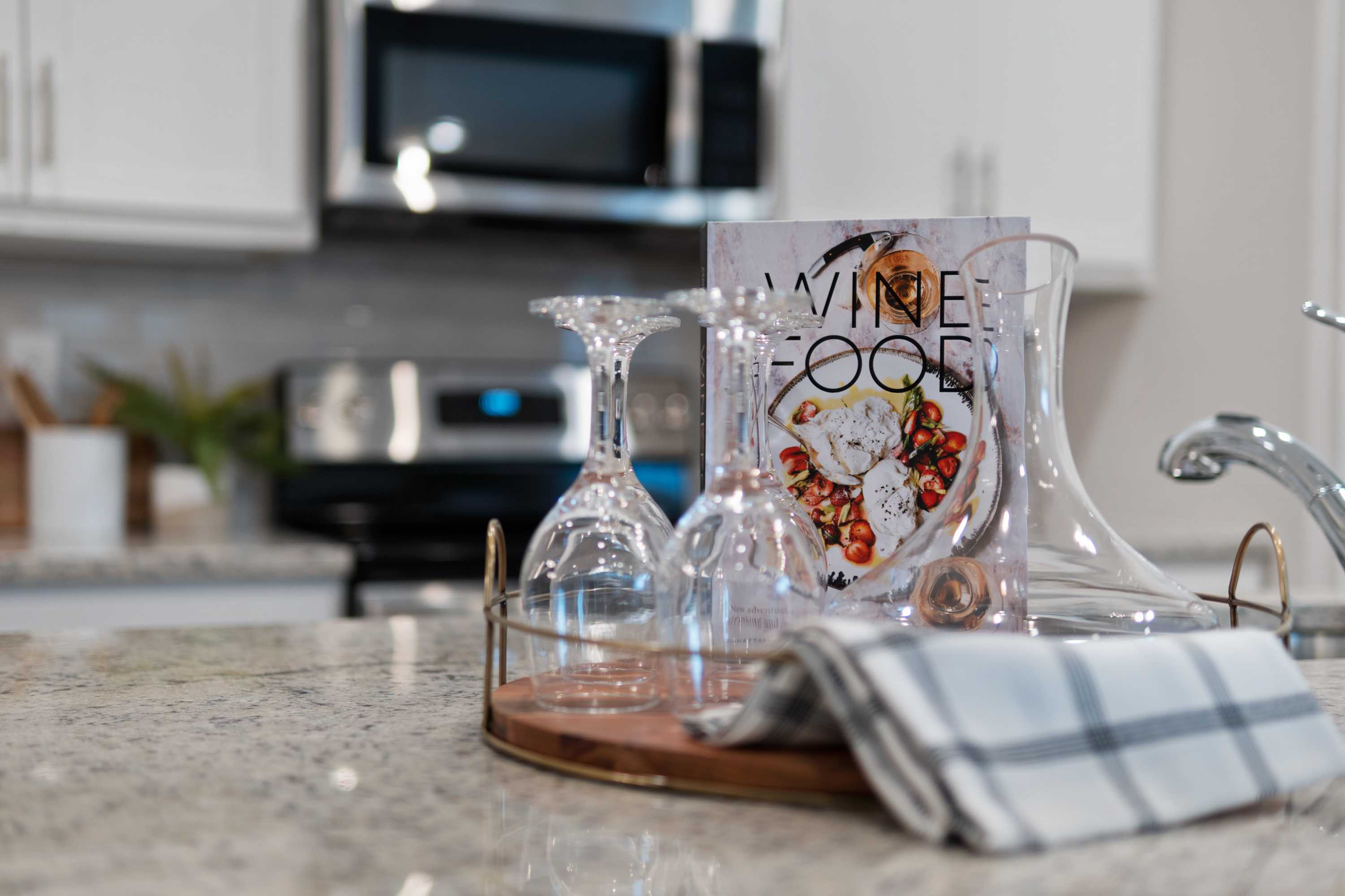 Modern kitchen at The Retreat at Cain Park in Hartselle Alabama with white cabinets, wine glasses, open cookbook, and carafe