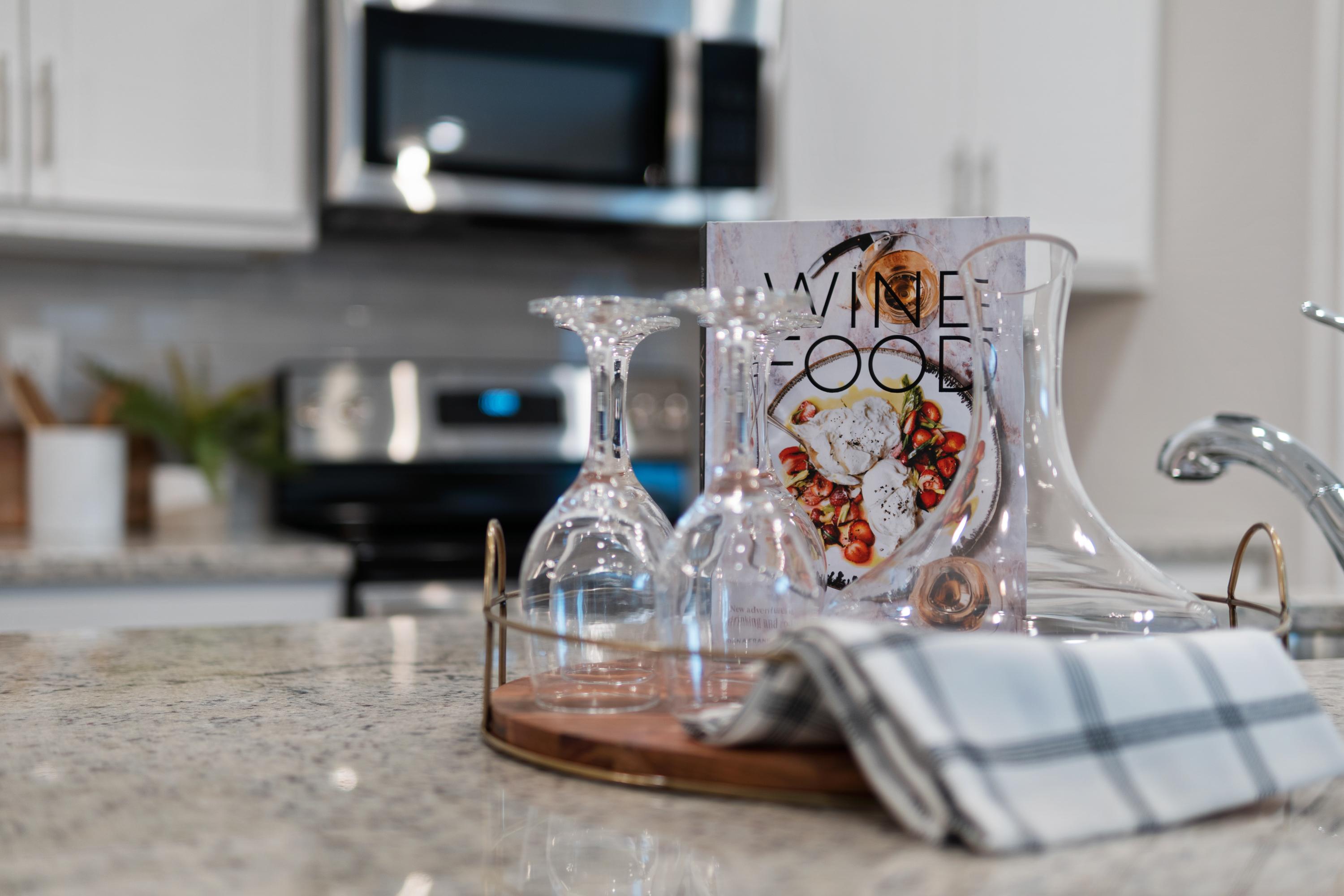 Modern kitchen at The Retreat at Cain Park in Hartselle Alabama with white cabinets, wine glasses, open cookbook, and carafe
