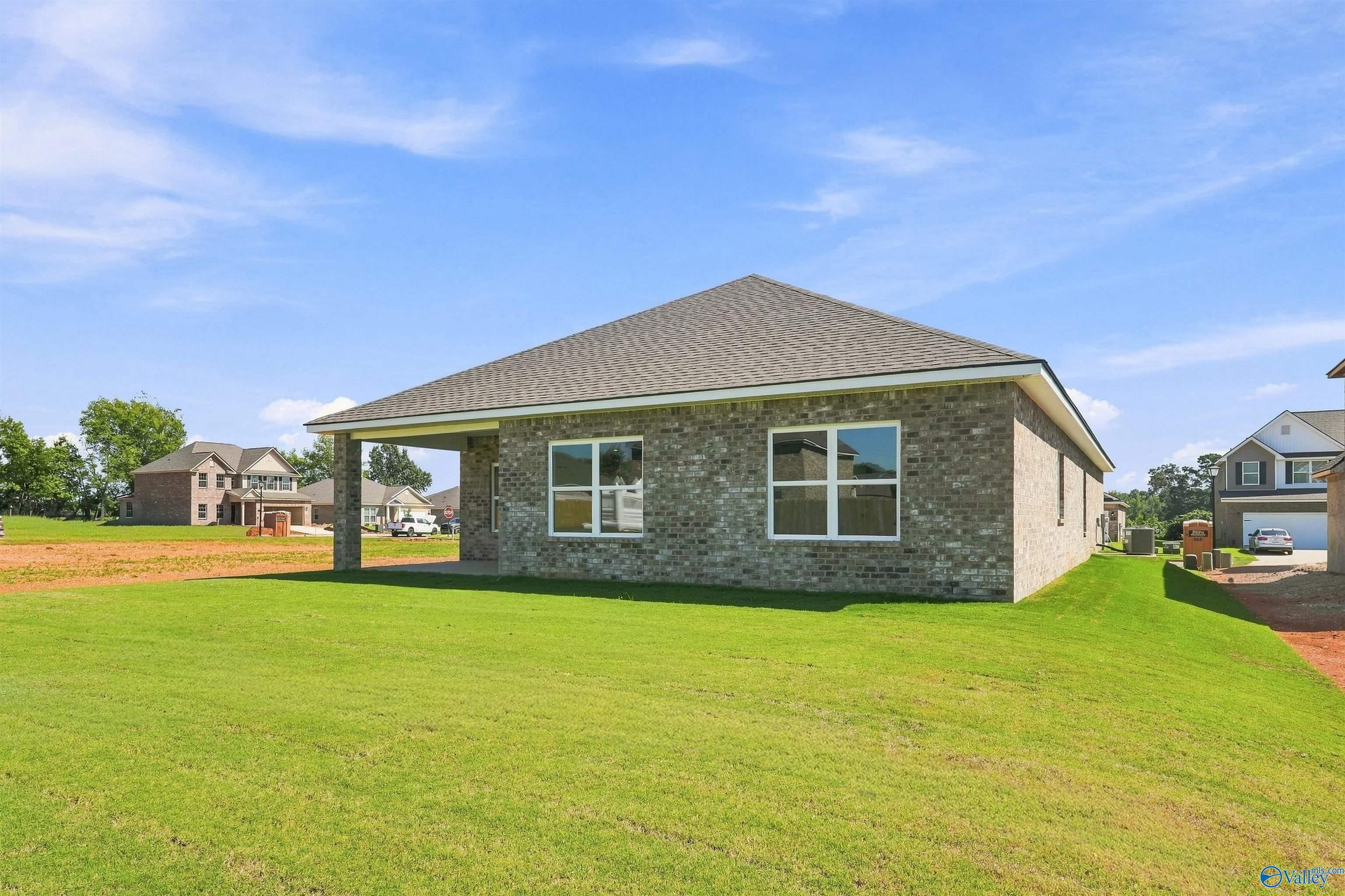 Brick single-story new construction home with covered patio and large green backyard in Ivy Hills, Toney, Alabama