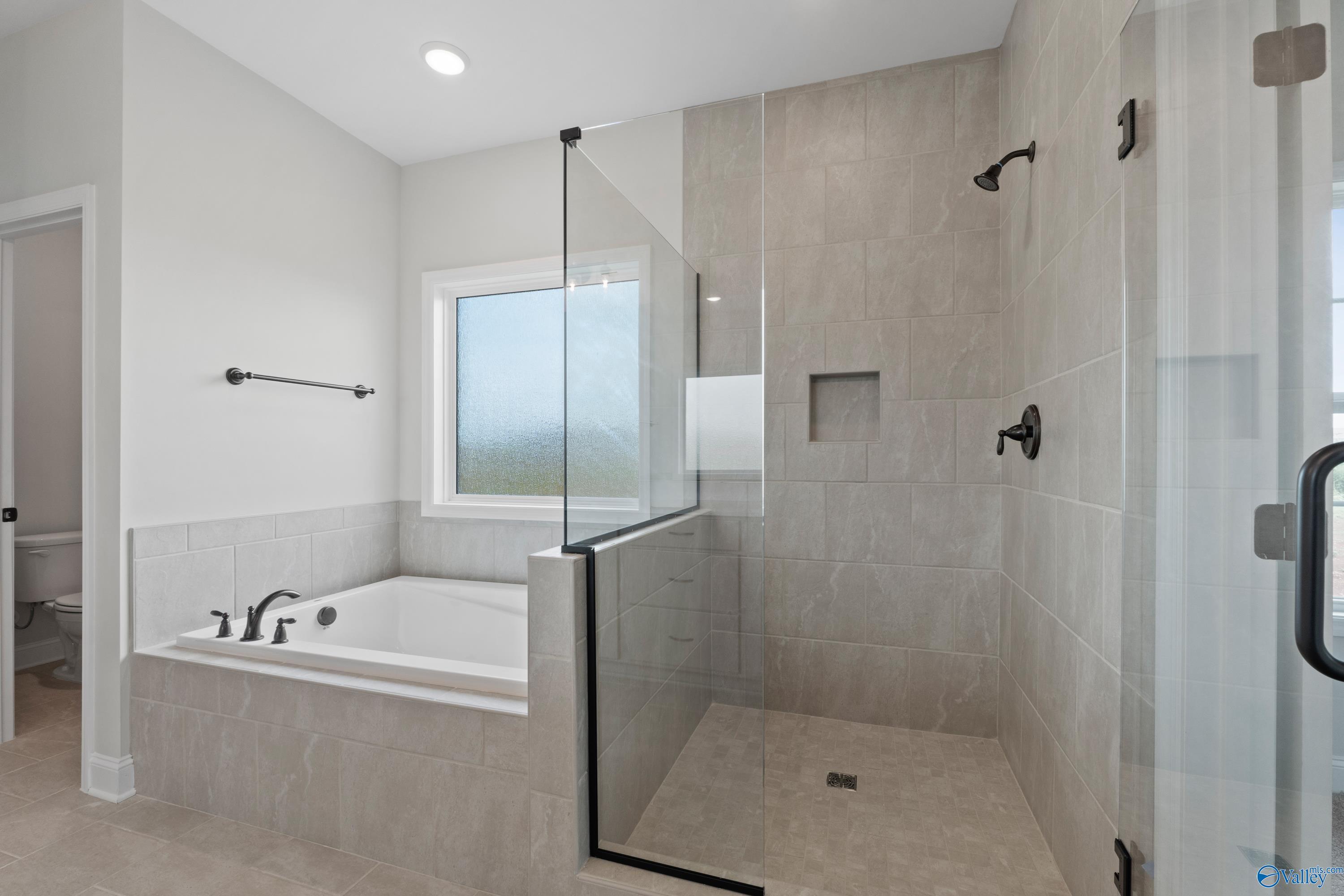 Modern master bathroom featuring glass-enclosed shower and freestanding tub in Davidson Homes The Kirkland, Harvest, Alabama
