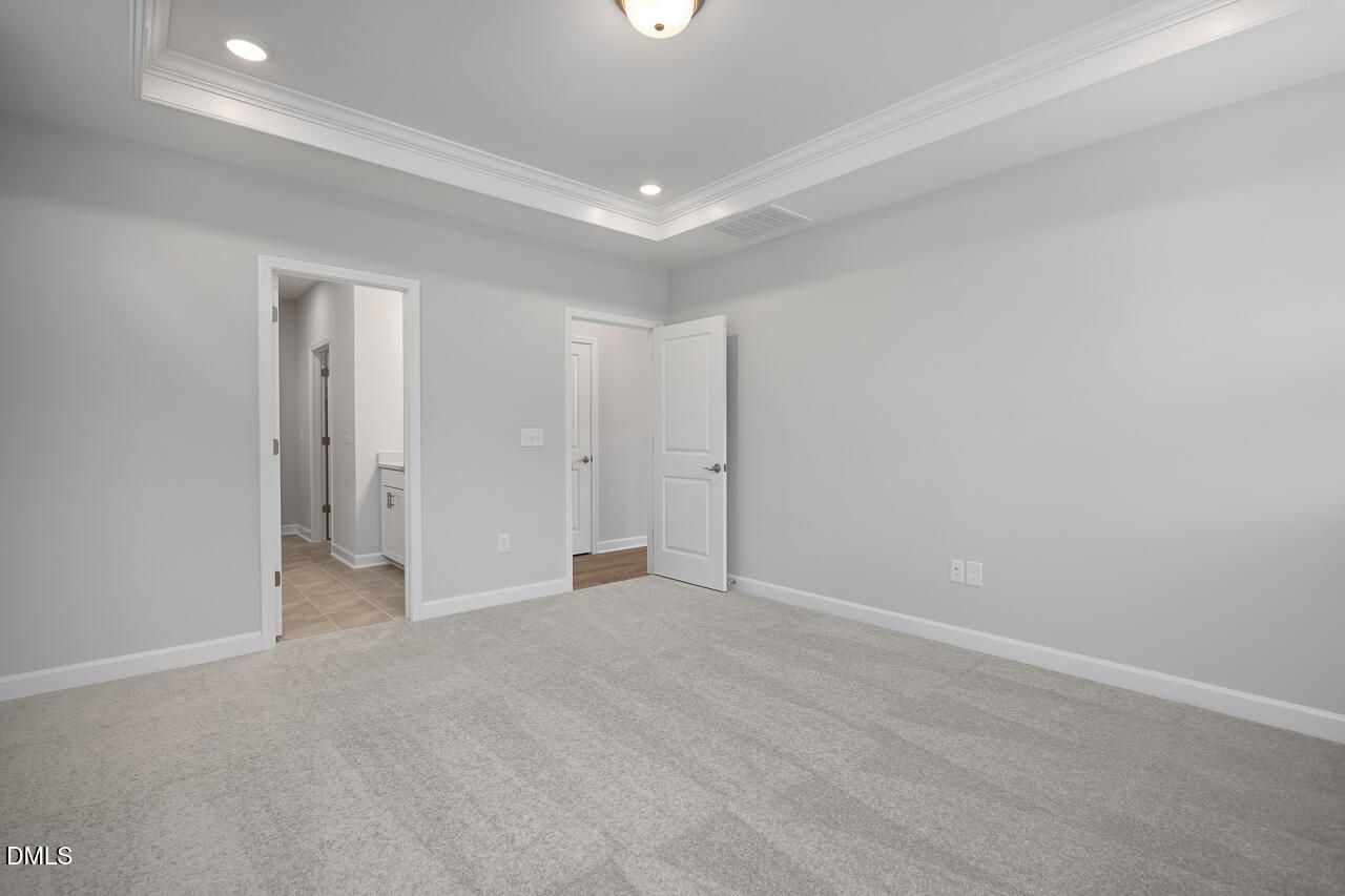 Spacious bedroom with tray ceiling in The Ashport L floor plan at Sage on North Main, Wake Forest, North Carolina.