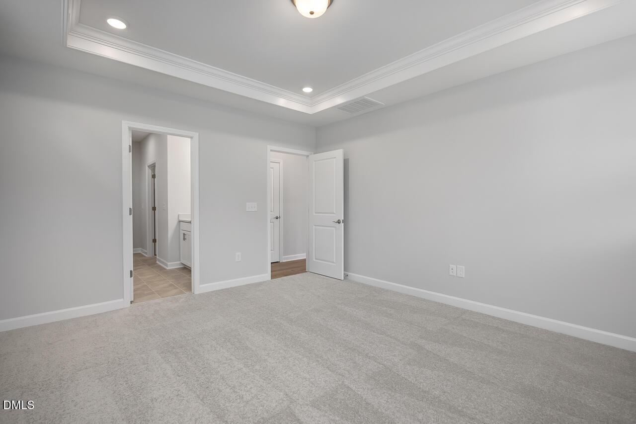 Spacious bedroom with tray ceiling in The Ashport L floor plan at Sage on North Main, Wake Forest, North Carolina.