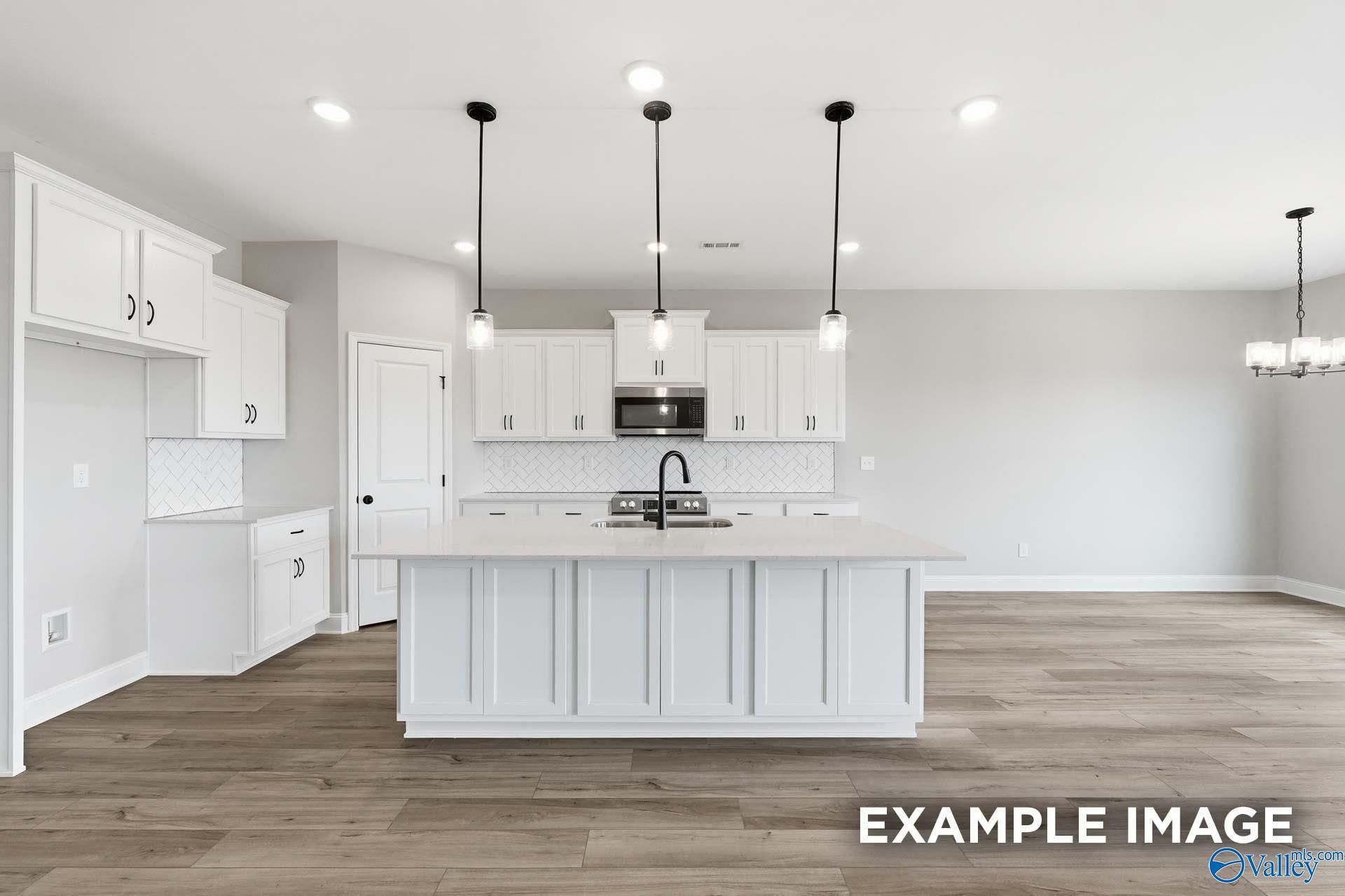 Bright kitchen with white cabinetry, large island, and pendant lights in Davidson Homes The Rockford C, Anderson Farm, Athens, AL
