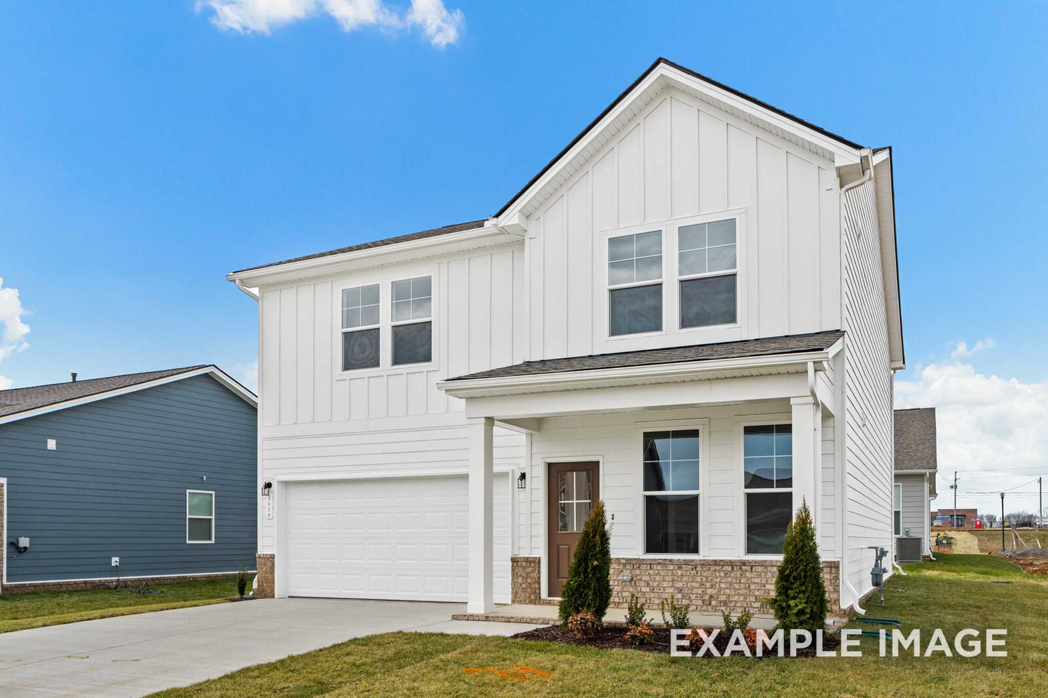 Modern farmhouse exterior of The Logan C two-story home with white board and batten siding, covered porch, and two-car garage in White House, TN