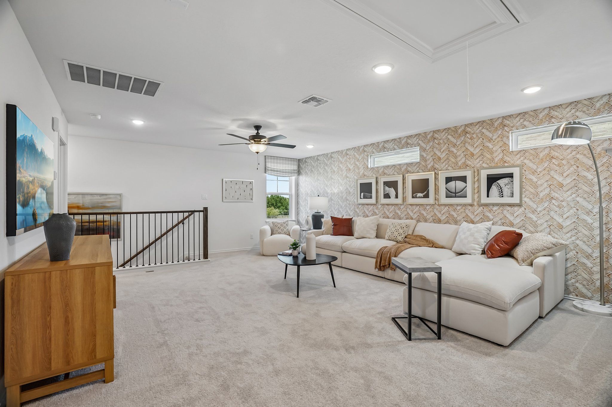 Spacious loft living area at Fairway Crossing in Converse, TX by Davidson Homes with herringbone accent wall and plush sofa.