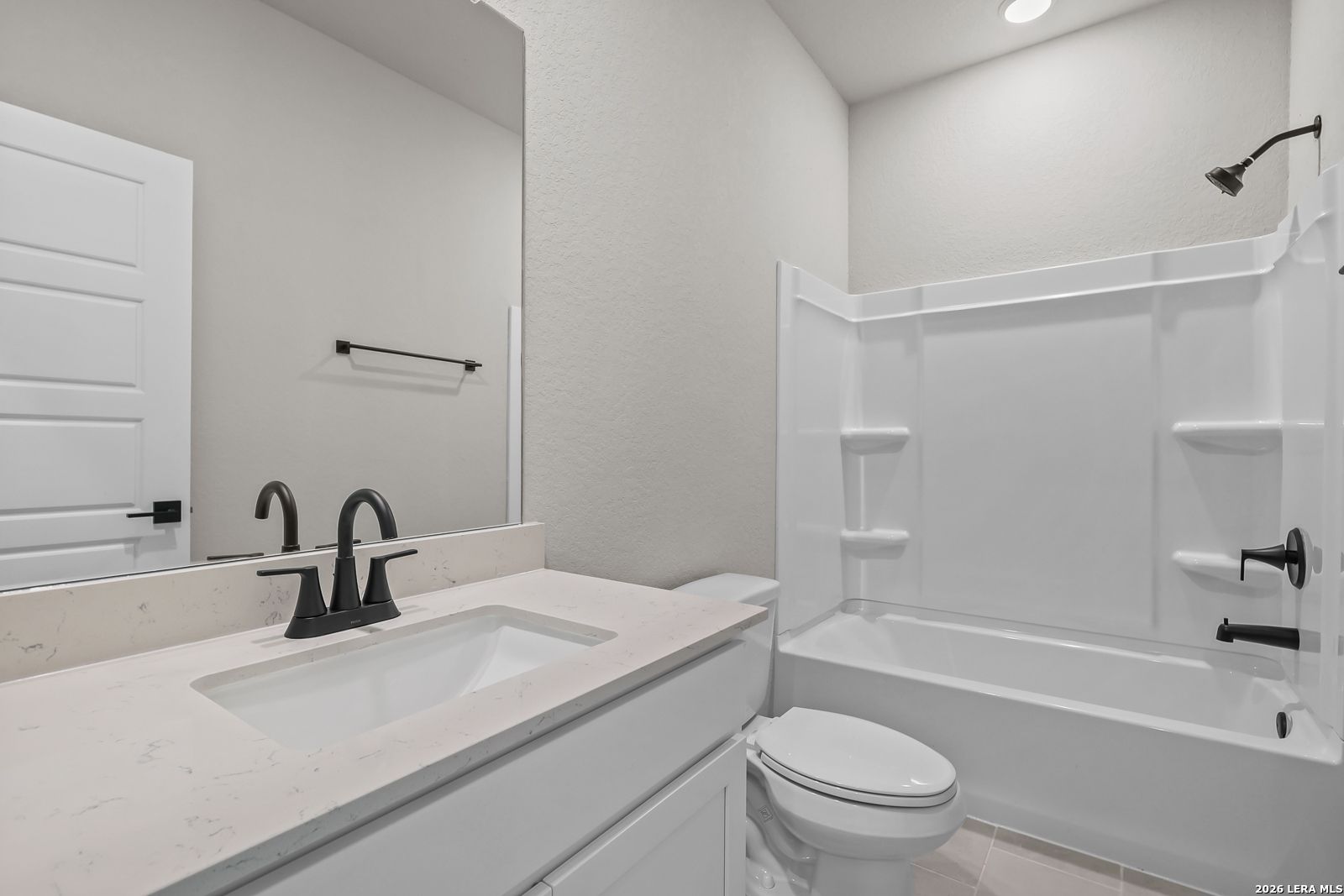 Modern bathroom with white vanity, quartz countertop, and black fixtures in a Davidson Homes Daphne H plan in Seguin, TX.