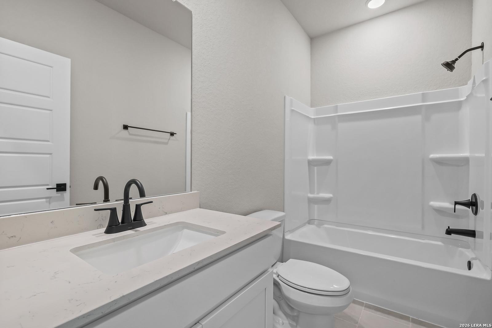 Modern bathroom with white vanity, quartz countertop, and black fixtures in a Davidson Homes Daphne H plan in Seguin, TX.