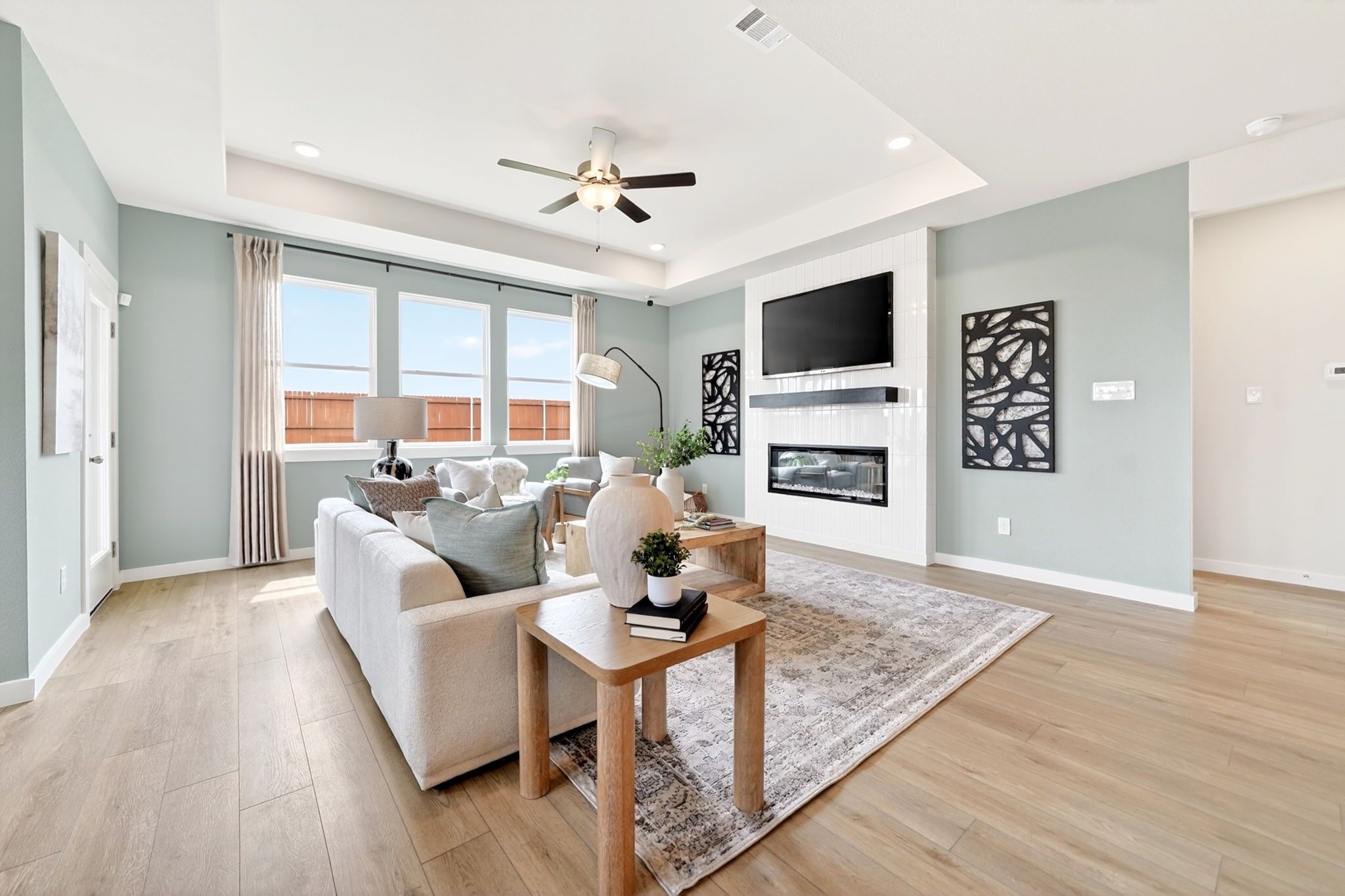 Bright living room with tray ceiling, fireplace, and hardwood floors in The Laurel M floor plan at Parks at Foster Crossing.