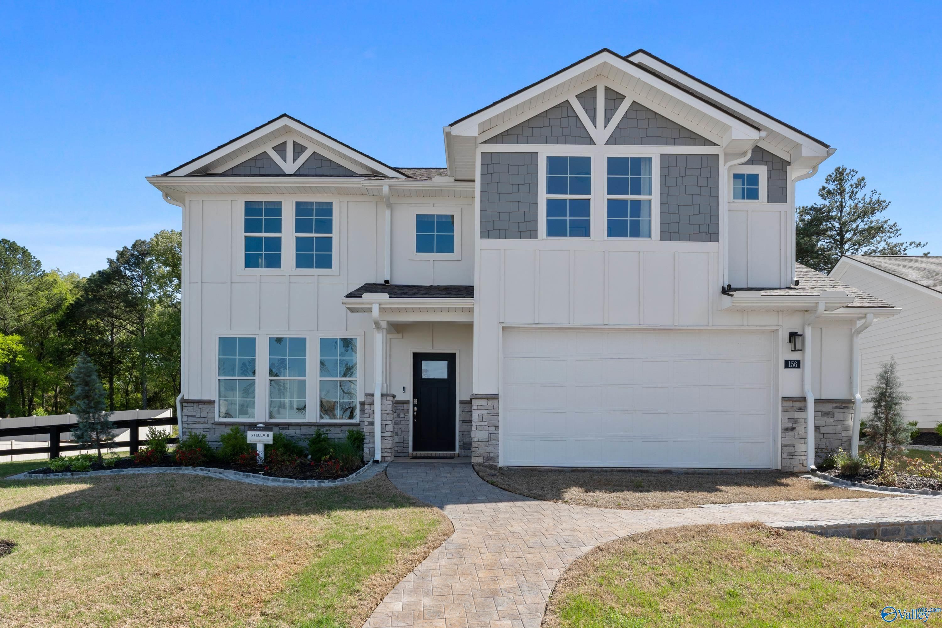 Modern two-story The Stella home by Davidson Homes: white siding, gray gables, two-car garage, stone accents, and landscaped yard in Evergreen Mill, Madison, AL