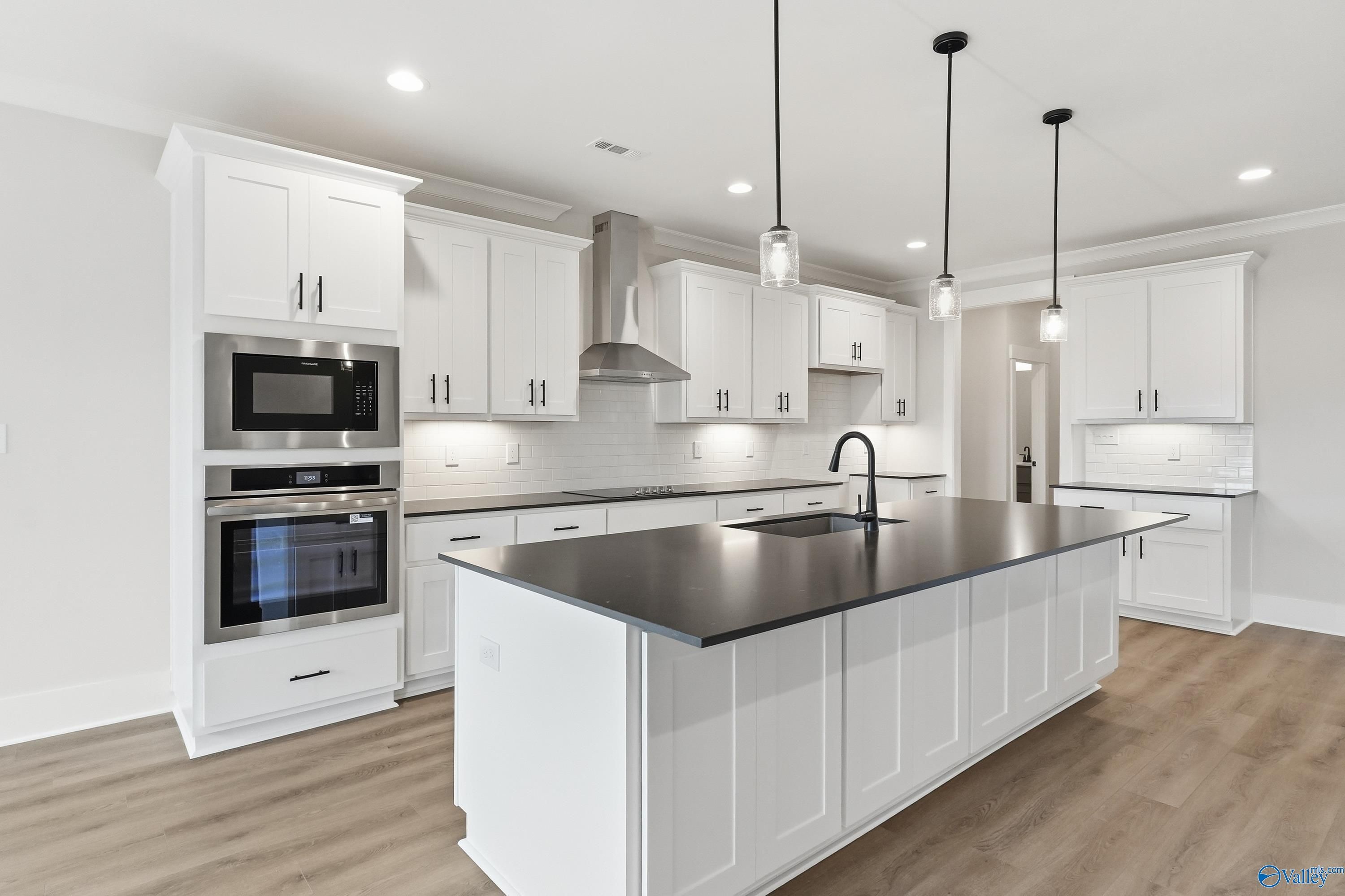 Modern kitchen featuring white shaker cabinets, black granite island, stainless steel appliances in The Finleigh by Davidson Homes, Meridianville, AL