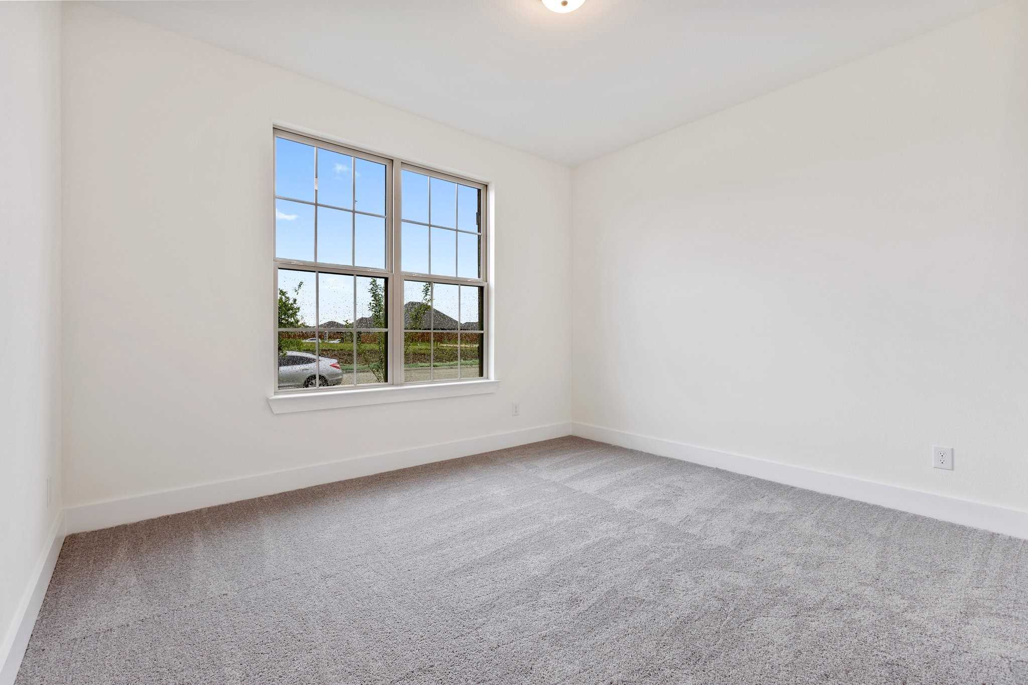 Bright secondary bedroom with large windows overlooking suburban view in Davidson Homes Rockford C, Josephine TX