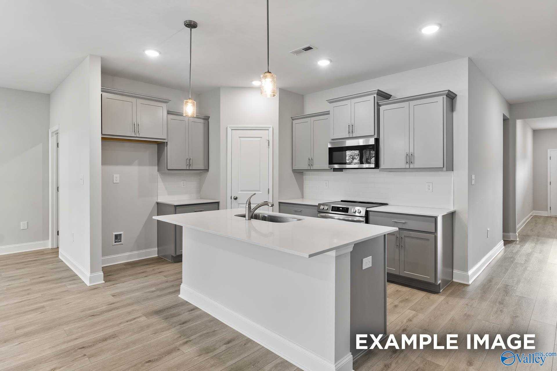 Modern open-concept kitchen featuring white island, gray cabinets, stainless appliances in The Daphne C by Davidson Homes, New Market, AL