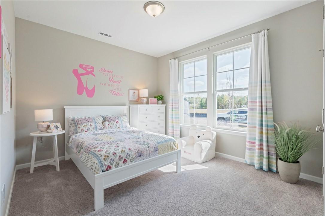 Cozy girl's bedroom with pink "Dream Big Princess" ballet decal, white bed, quilt, and large windows in Davidson Homes The Phoenix B, Opelika