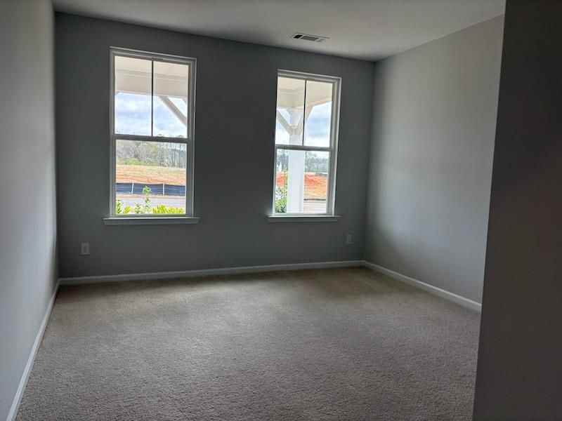Bright secondary bedroom with large windows, gray walls, and beige carpet in Davidson Homes The Hickory B, Winder, GA