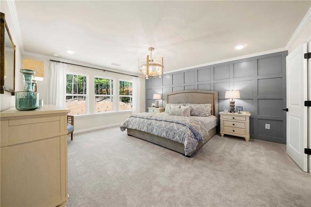 Elegant master bedroom with king bed, gray shiplap accent wall, chandelier, and windows in Davidson Homes The Hickory B, Riverwood, Dallas, GA