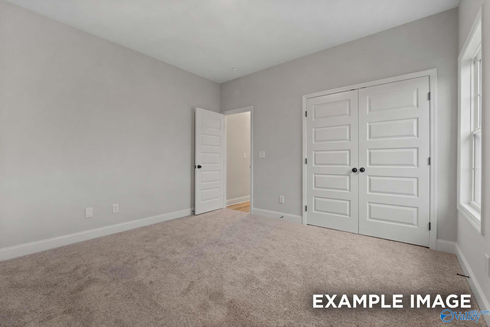 Spacious empty bedroom with gray walls, beige carpet, double closet doors in Davidson Homes The Finleigh, Meridianville, Alabama