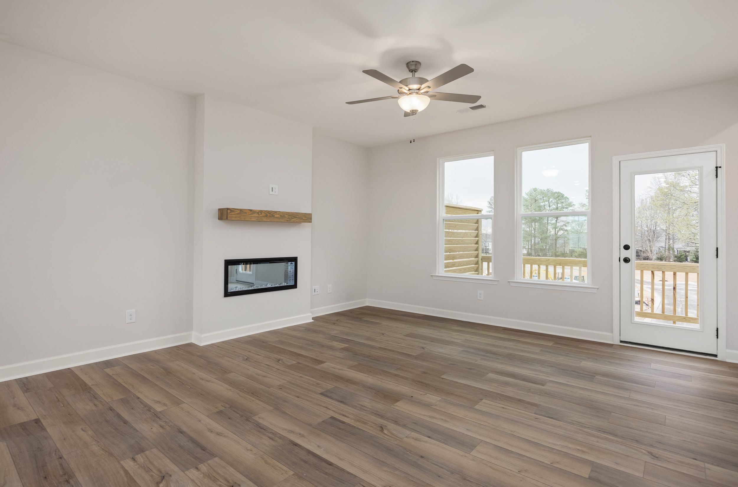 Spacious living room at Forestville Yard Townhomes in Knightdale NC with modern fireplace, hardwood floors, and deck access
