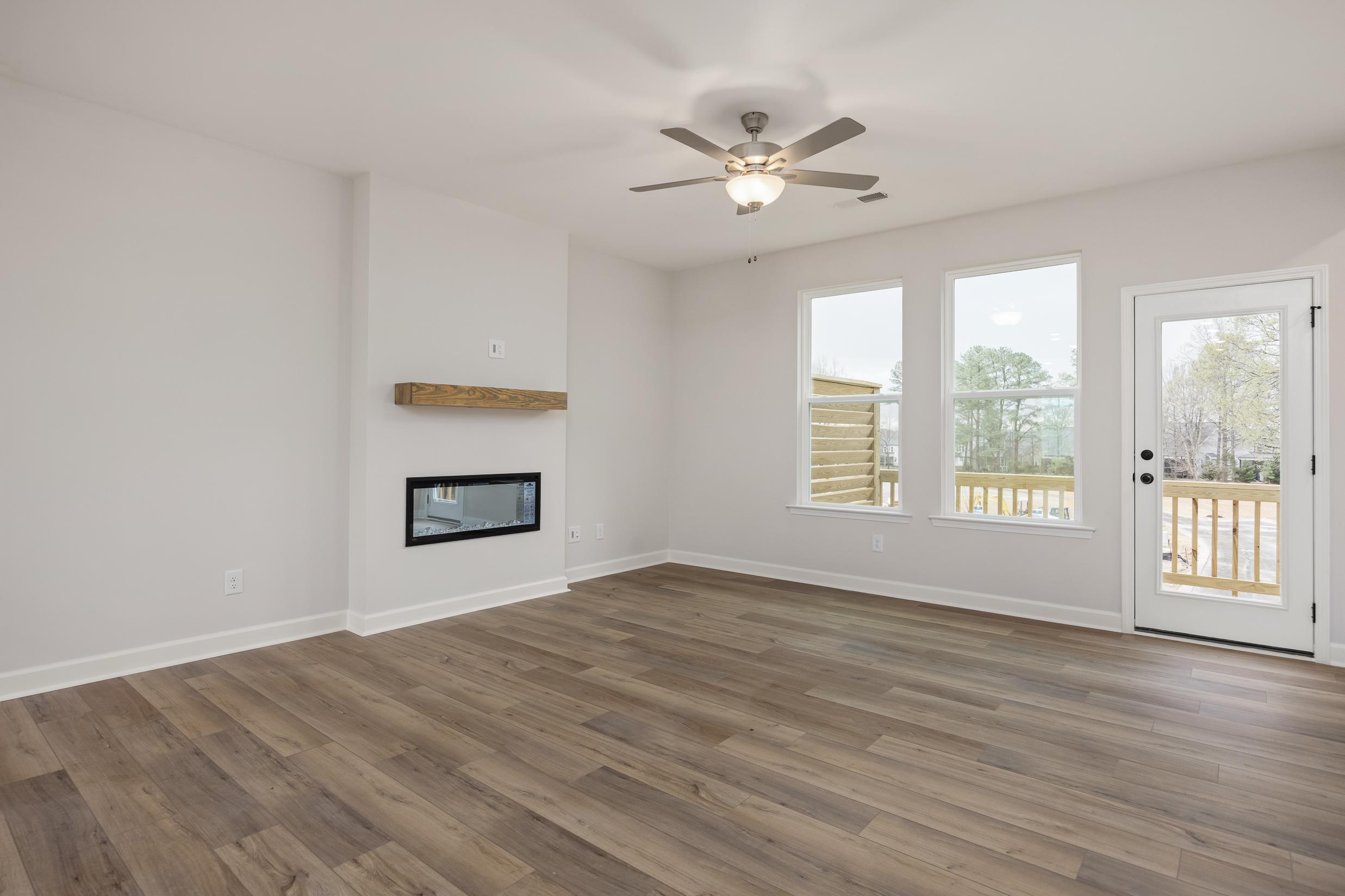 Spacious living room at Forestville Yard Townhomes in Knightdale NC with modern fireplace, hardwood floors, and deck access