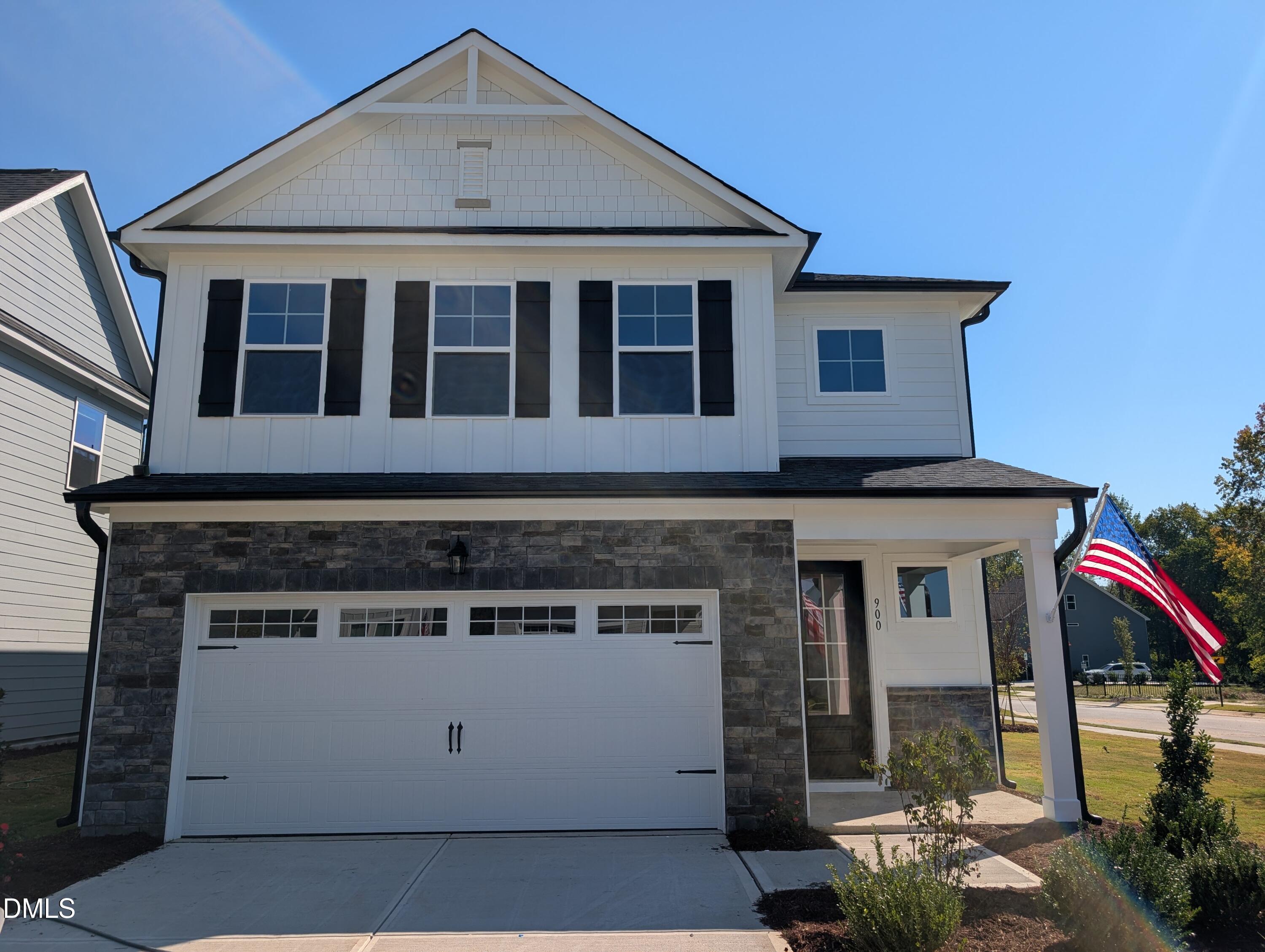Two-story white and stone exterior with black shutters and 2-car garage at Davidson Homes The Preston C in Wendell Ridge, NC