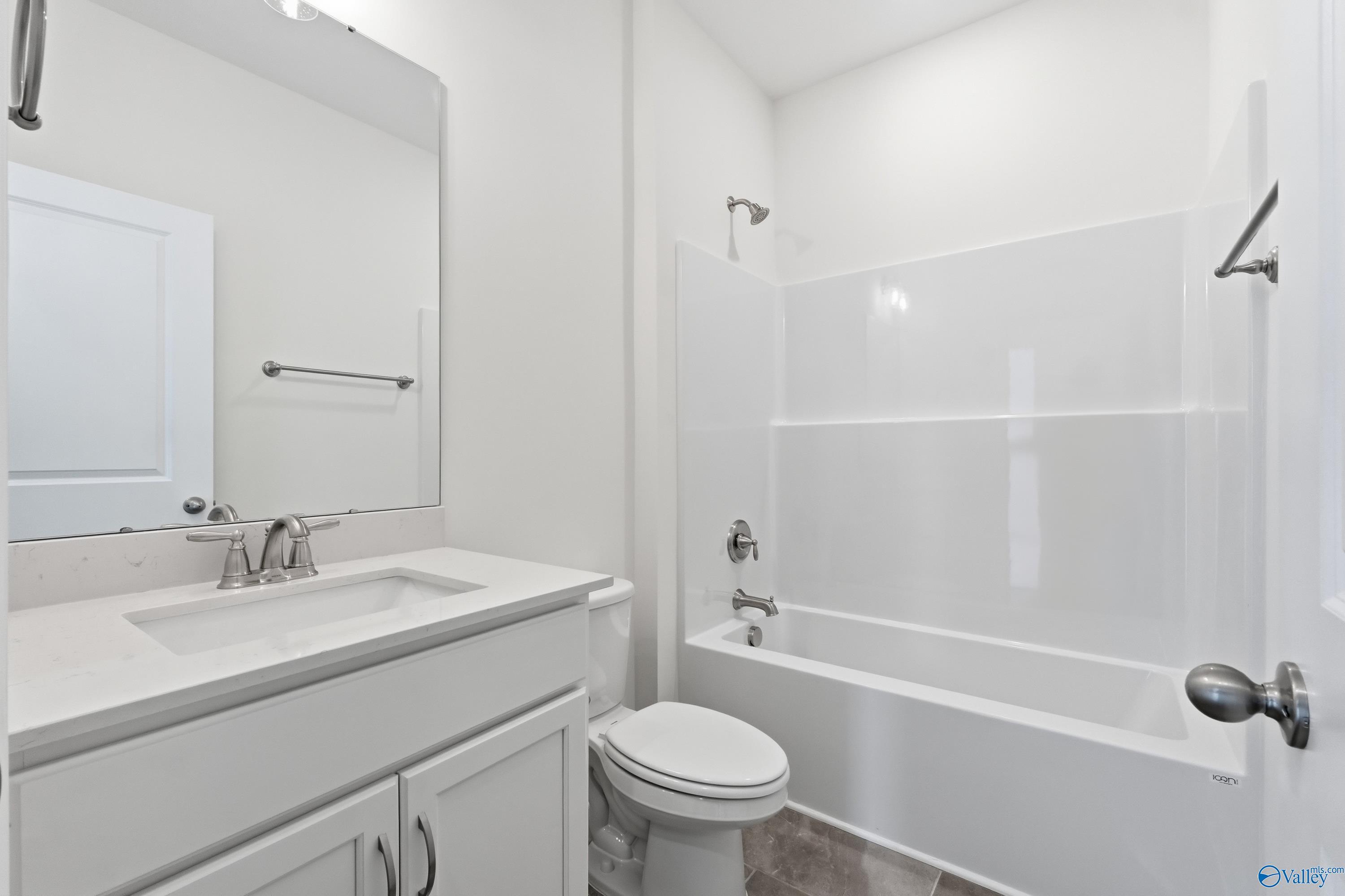 Modern guest bathroom with white subway tile tub-shower combo, vanity, and toilet in Davidson Homes The Montgomery C, Harvest, AL