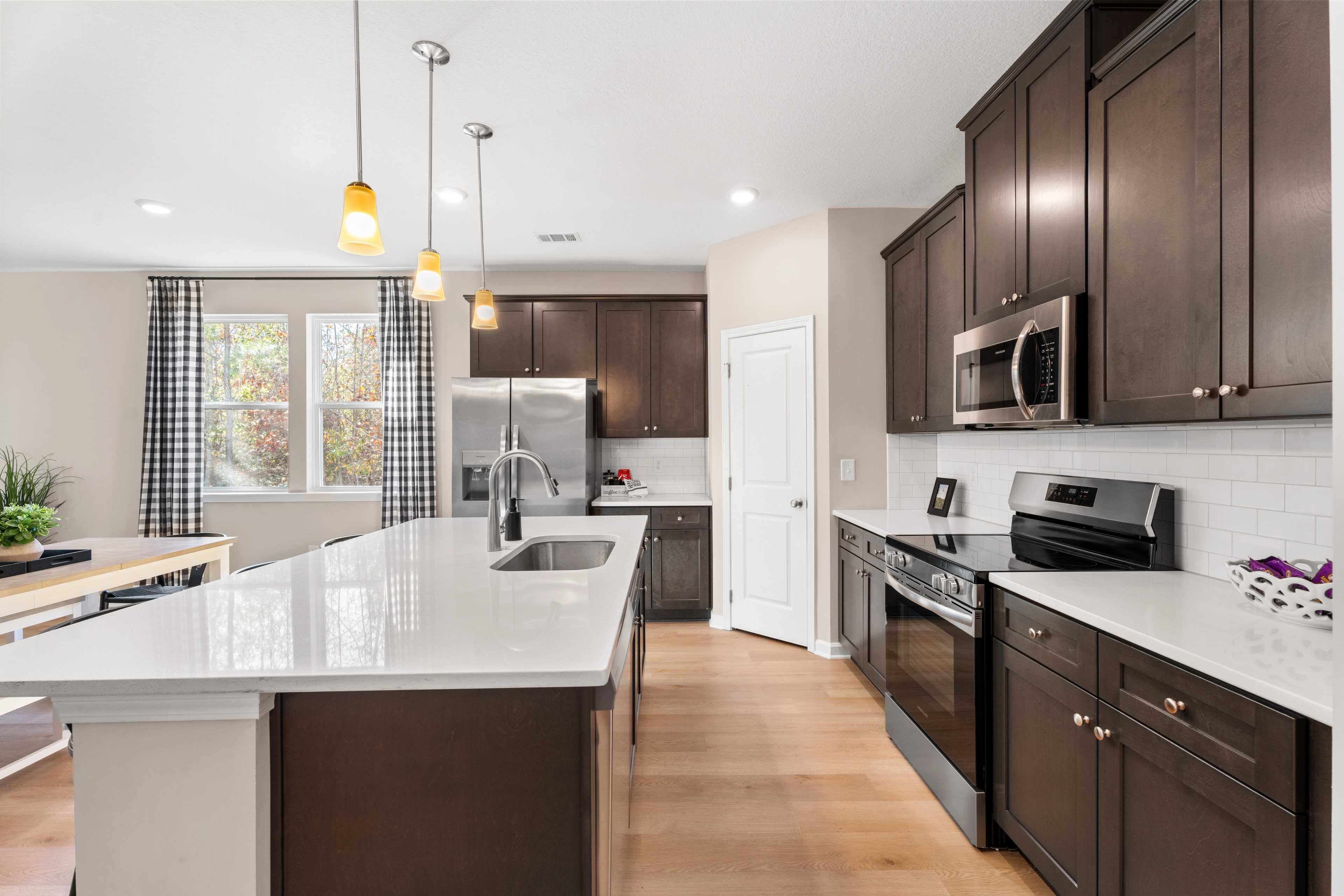 Spacious open-concept kitchen dining area in Silver Oak Cusseta Alabama with white cabinets hardwood floors and pendant lights