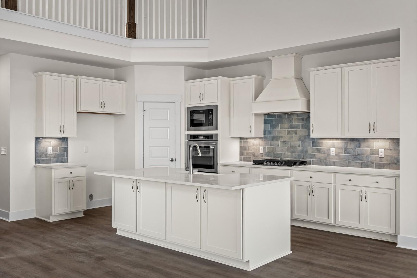 Modern white kitchen with island, blue tile backsplash, and stainless appliances in The Ridgeport D, Mt. Juliet, Tennessee.
