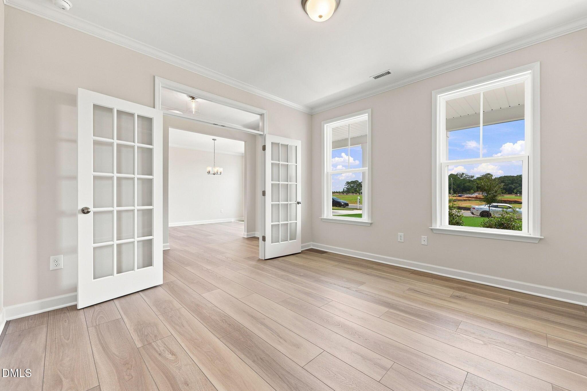 Bright flex room with French doors and wood-look flooring in The Magnolia B floor plan, Retreat at North Main, Lillington.