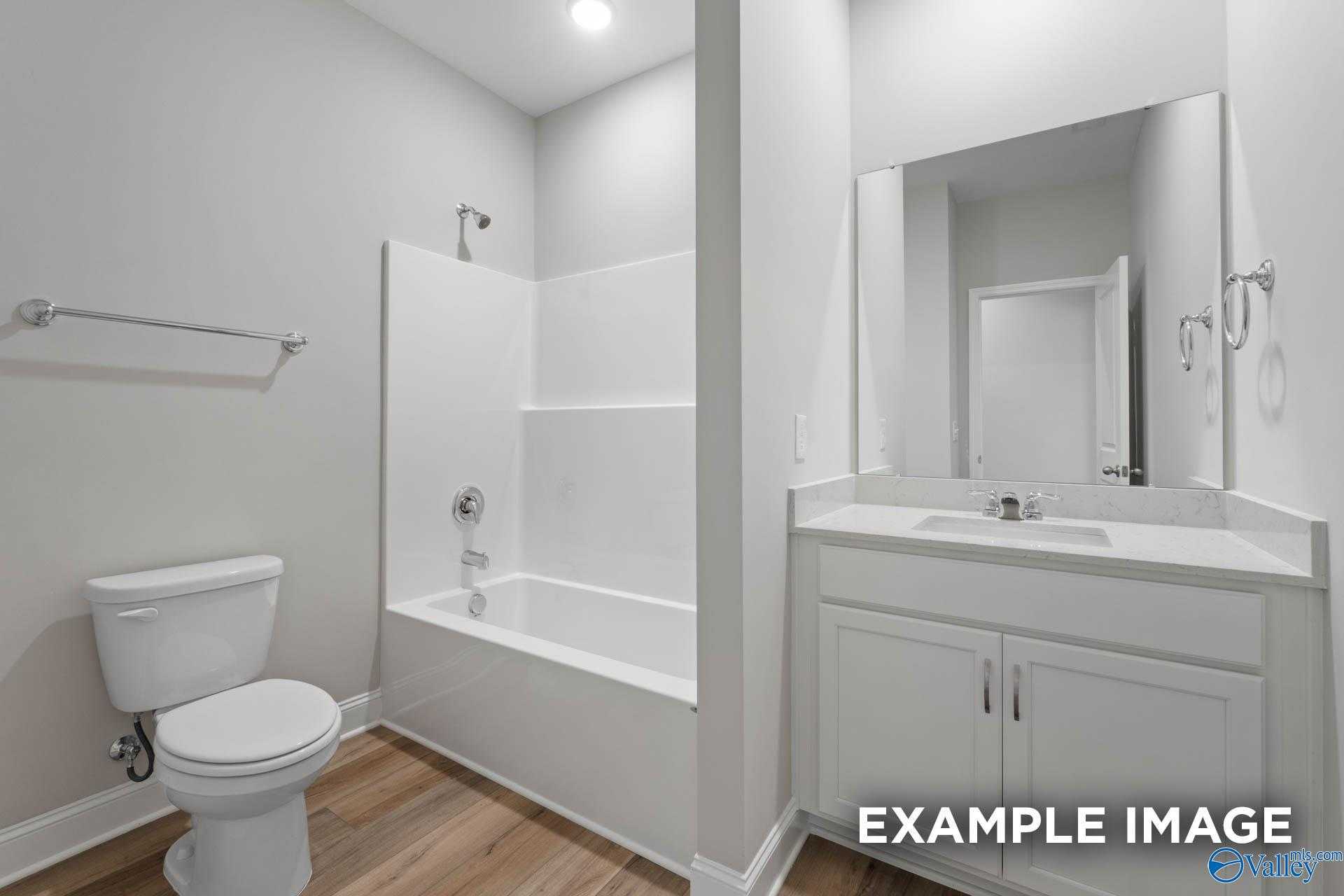 Modern bathroom with white tiled walk-in shower, tub combo, dual sinks, and wood floors in Davidson Homes The Everett, Meridianville, Alabama