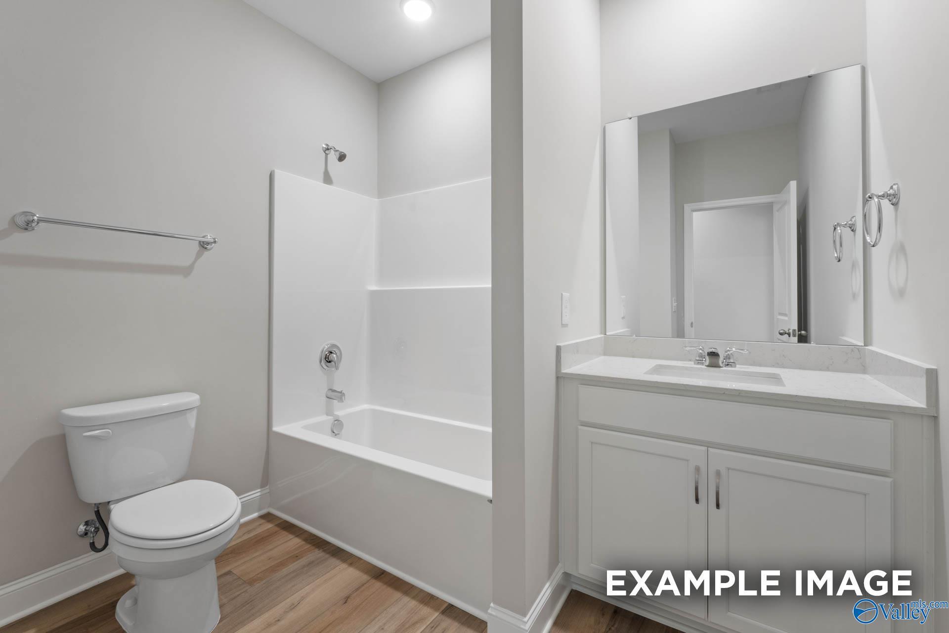 Contemporary bathroom with tub-shower combo, white vanity, and mirror in Davidson Homes The Everett B, Athens, Alabama
