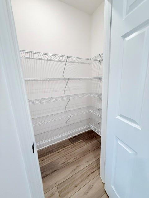 Walk-in pantry with white wire shelving and wood-look flooring in The Hickory B home at Wehunt Meadows, Hoschton, Georgia.